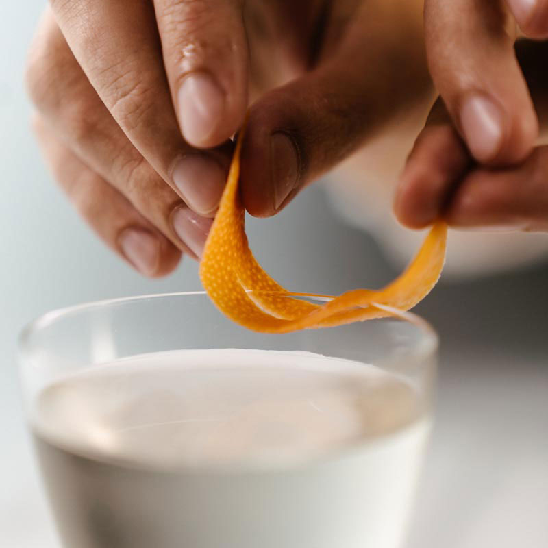 Macro shot of an orange peel being placed on a cocktail