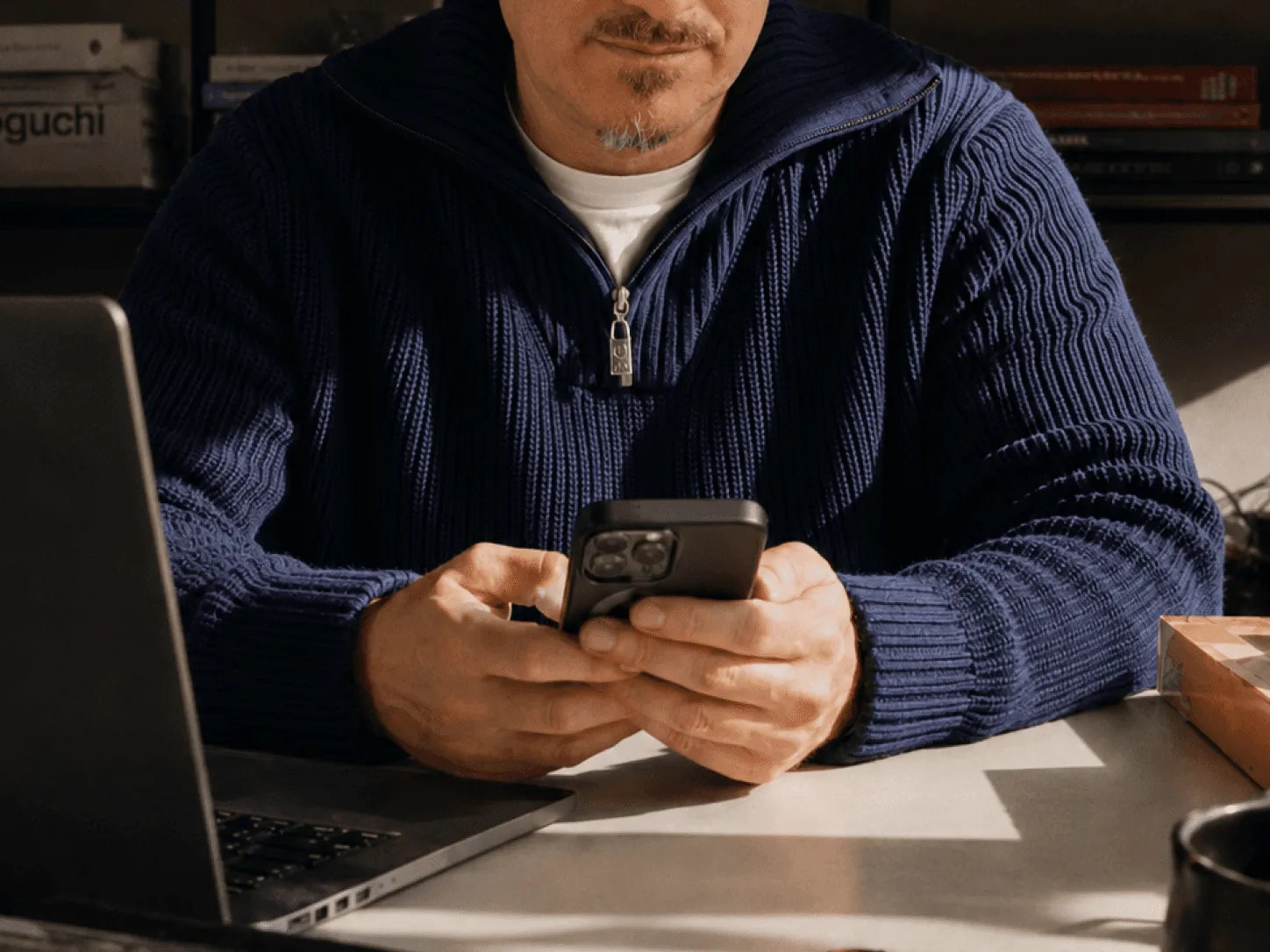Mann am Schreibtisch mit Handy in der Hand