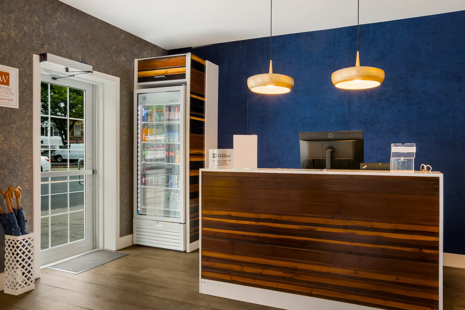 Reception desk with computer monitor and mini-fridge in a hotel lobby.