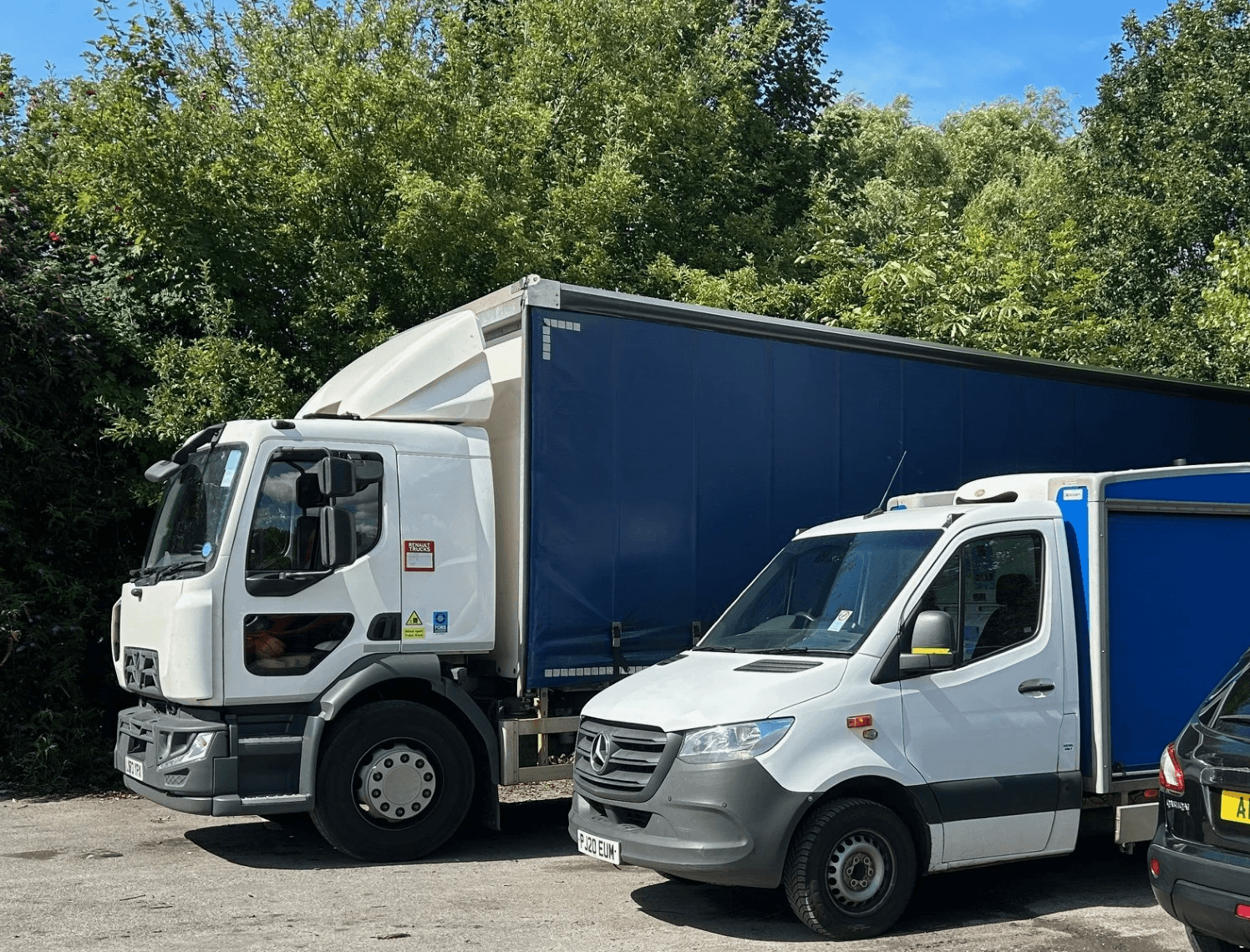 Image of a luton van with a blue body in front of a large haulage vehicle with a blue trailer