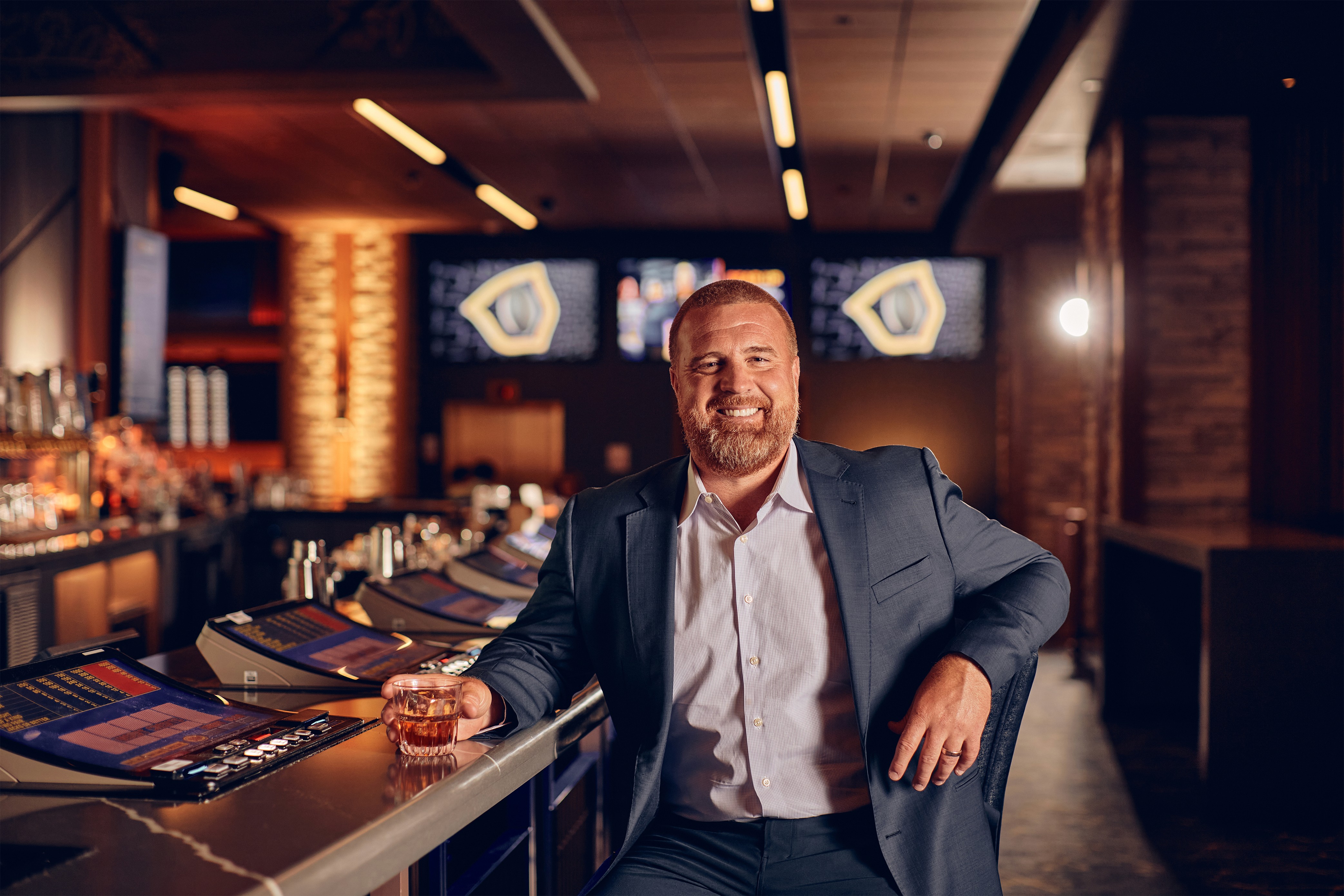 John Kuhn in suit with drink sits at bar