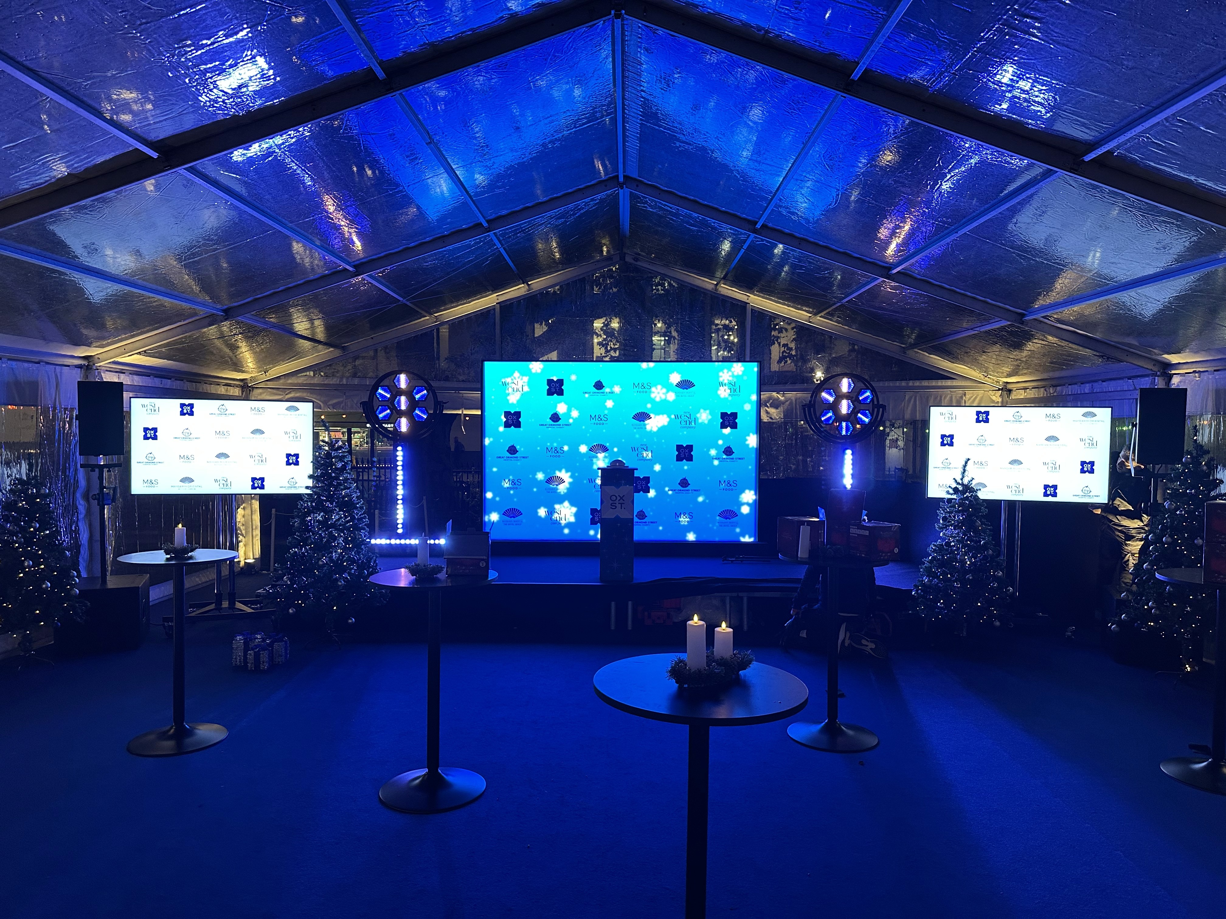 Stage, LED video wall, relay screens and blue lighting inside the Oxford Street Christmas Lights Switch-On marquee.
