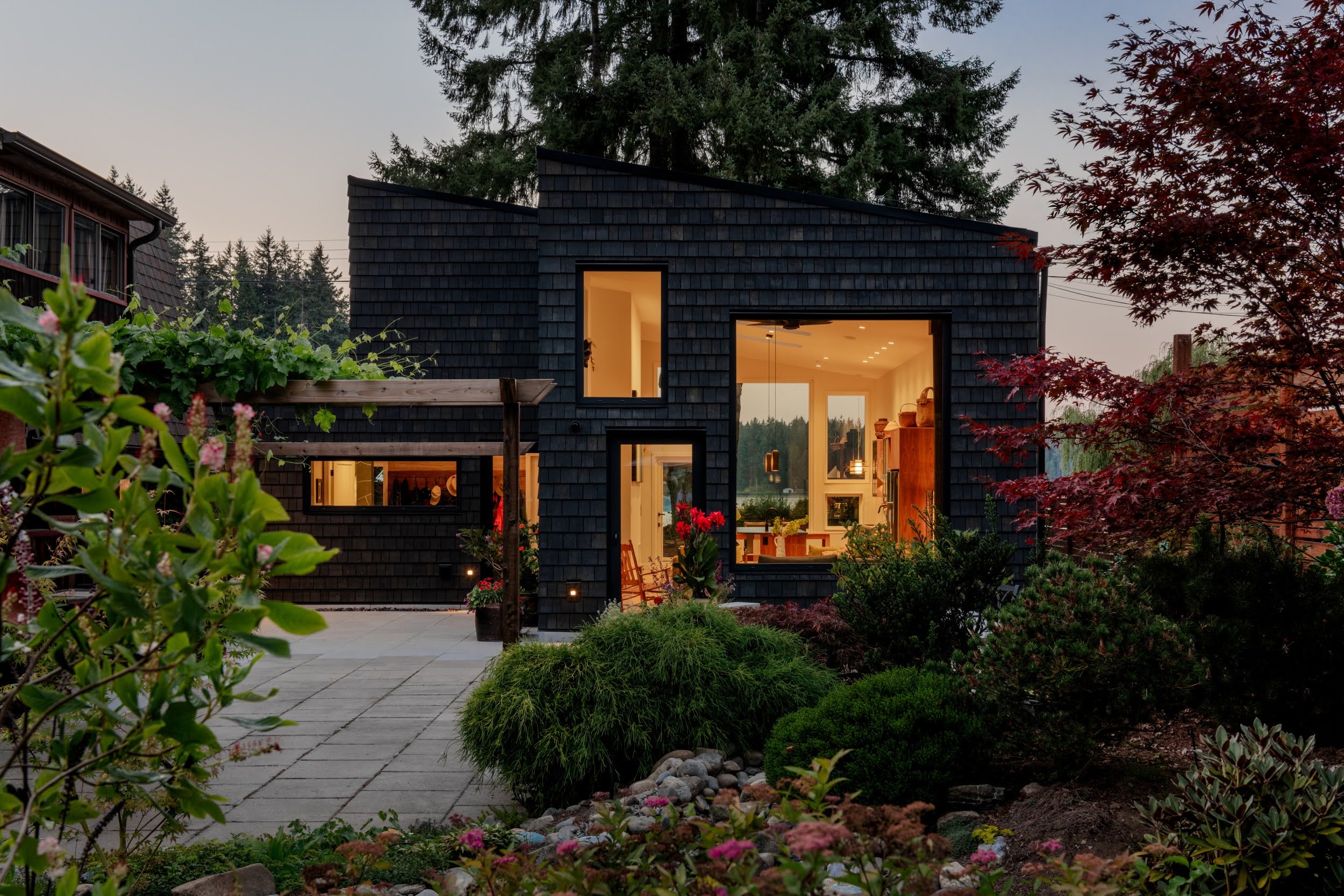 Modern indoor space with large glass doors, lush greenery, and a cozy seating area visible beyond.