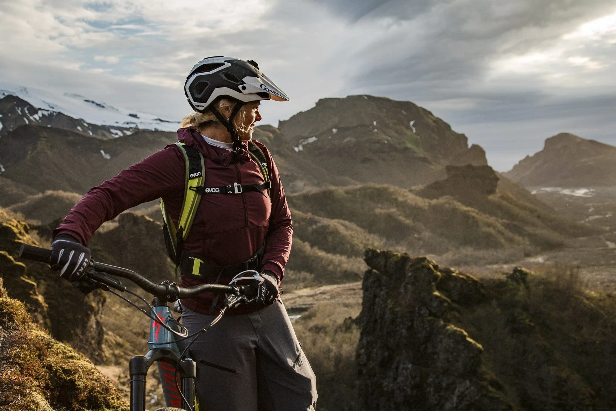 Cyclist resting with a mountain bike at a viewpoint above rugged peaks.