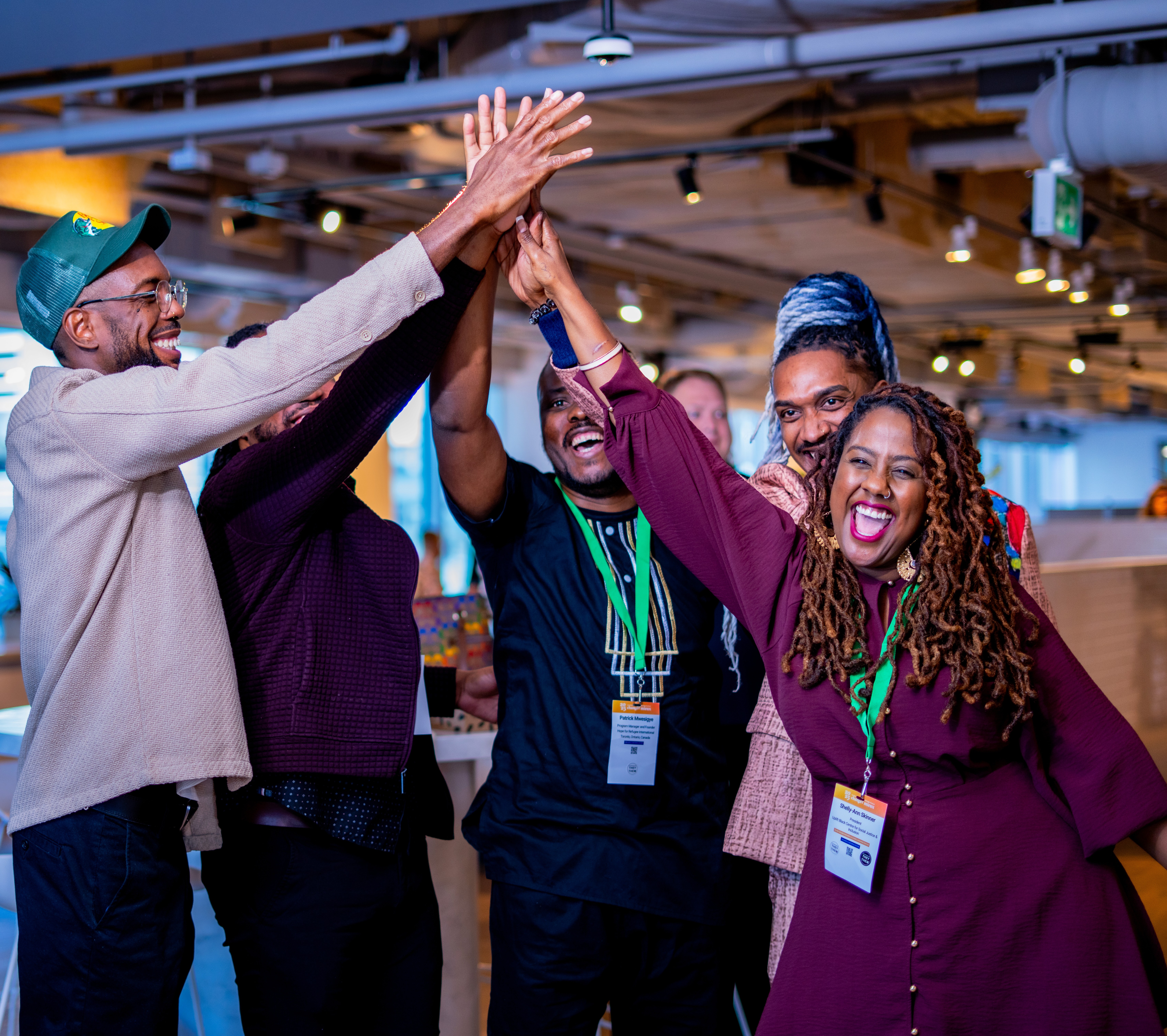 A diverse group of six people standing together in front of colorful urban street art, smiling and enjoying the moment.