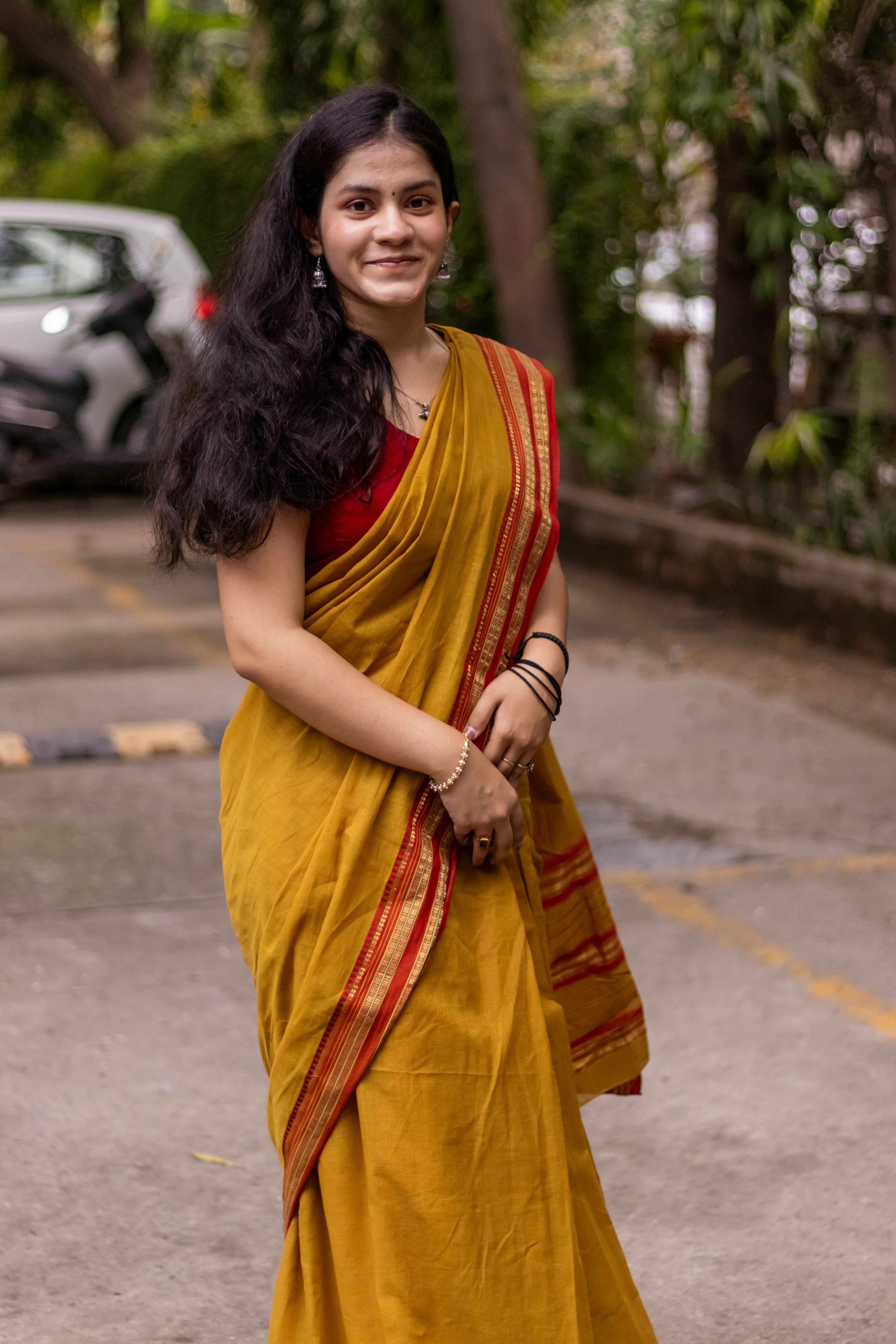 A woman in a yellow sari standing in a parking lot