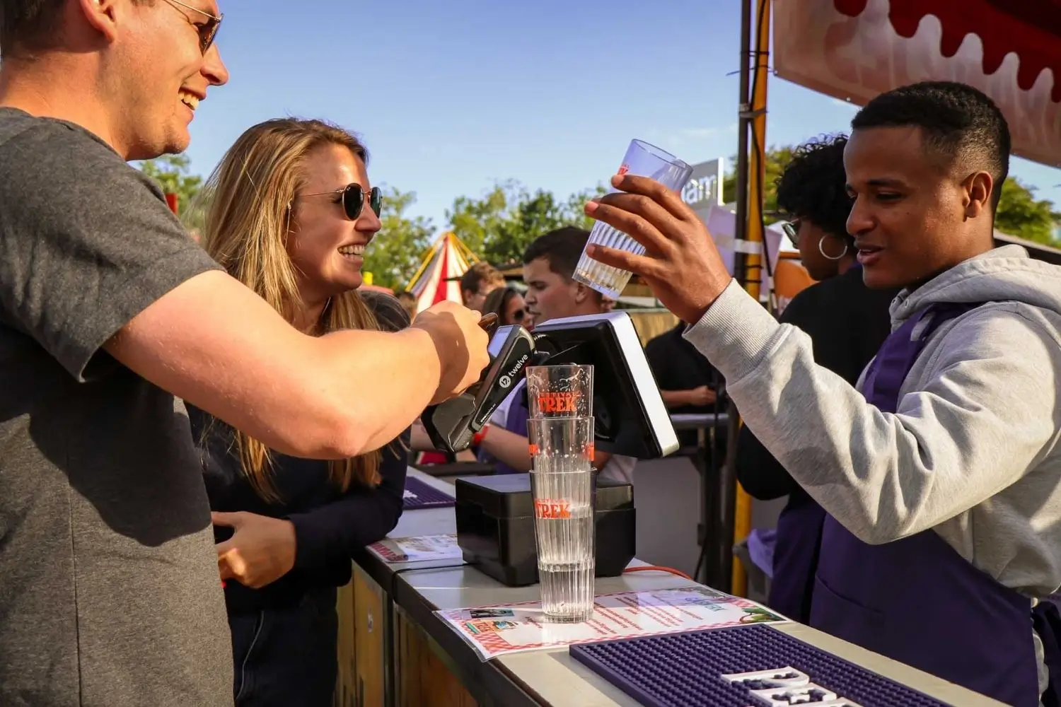man die een drankje koopt achter een bar waar een betaalsysteem opstaat