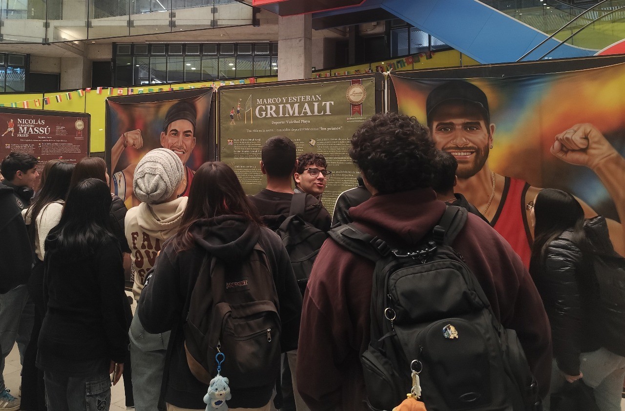 Espectadores observando la pintura de los Primos Grimalt, voleibolistas de playa chilenos, en la exposición Leyendas del Deporte en USACH.