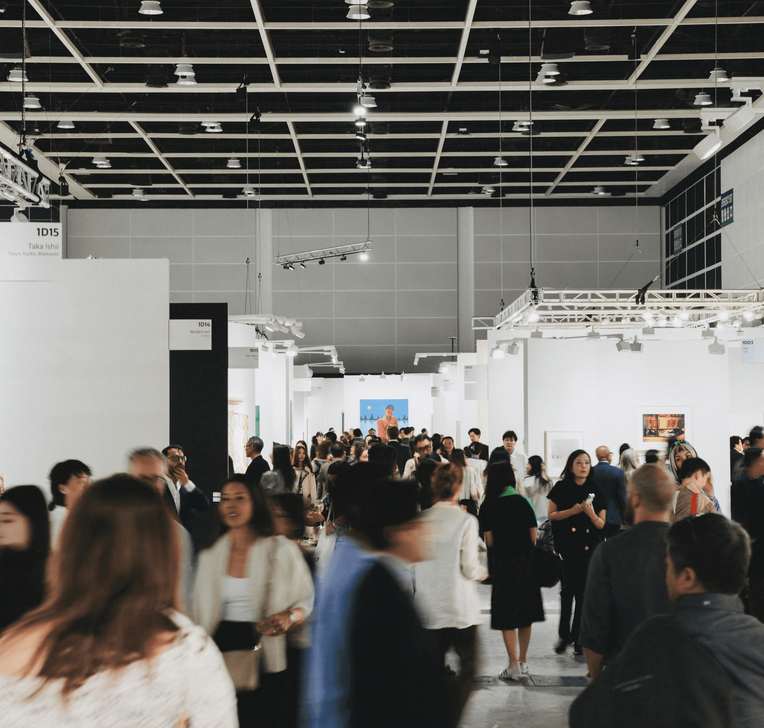 People browse art in a busy, modern gallery.