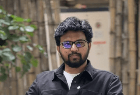 A professional business meeting with a presentation of data charts, featuring three formally dressed individuals in a modern office setting.