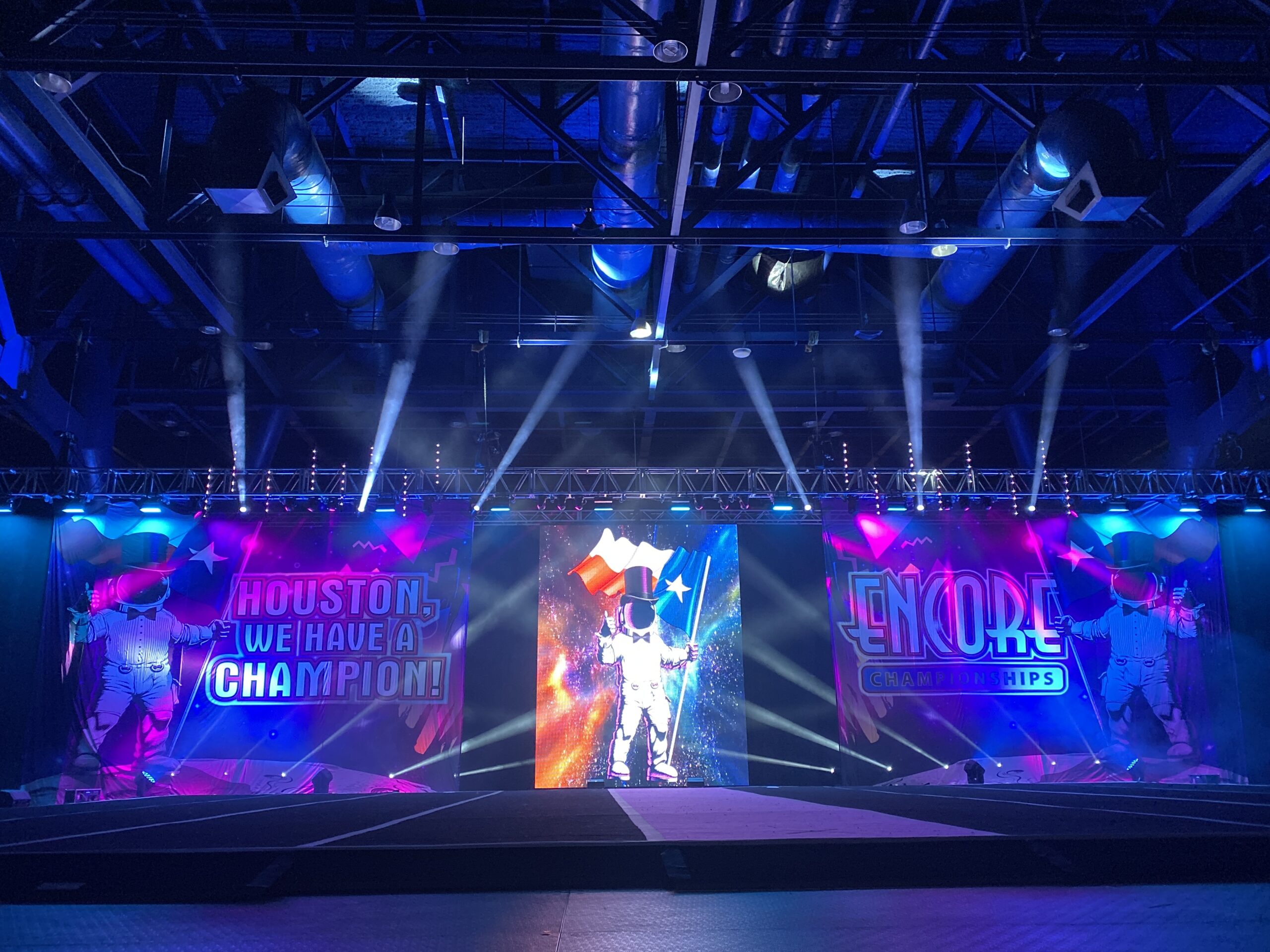 Cheer competition stage with large LED video walls and blue stage lighting