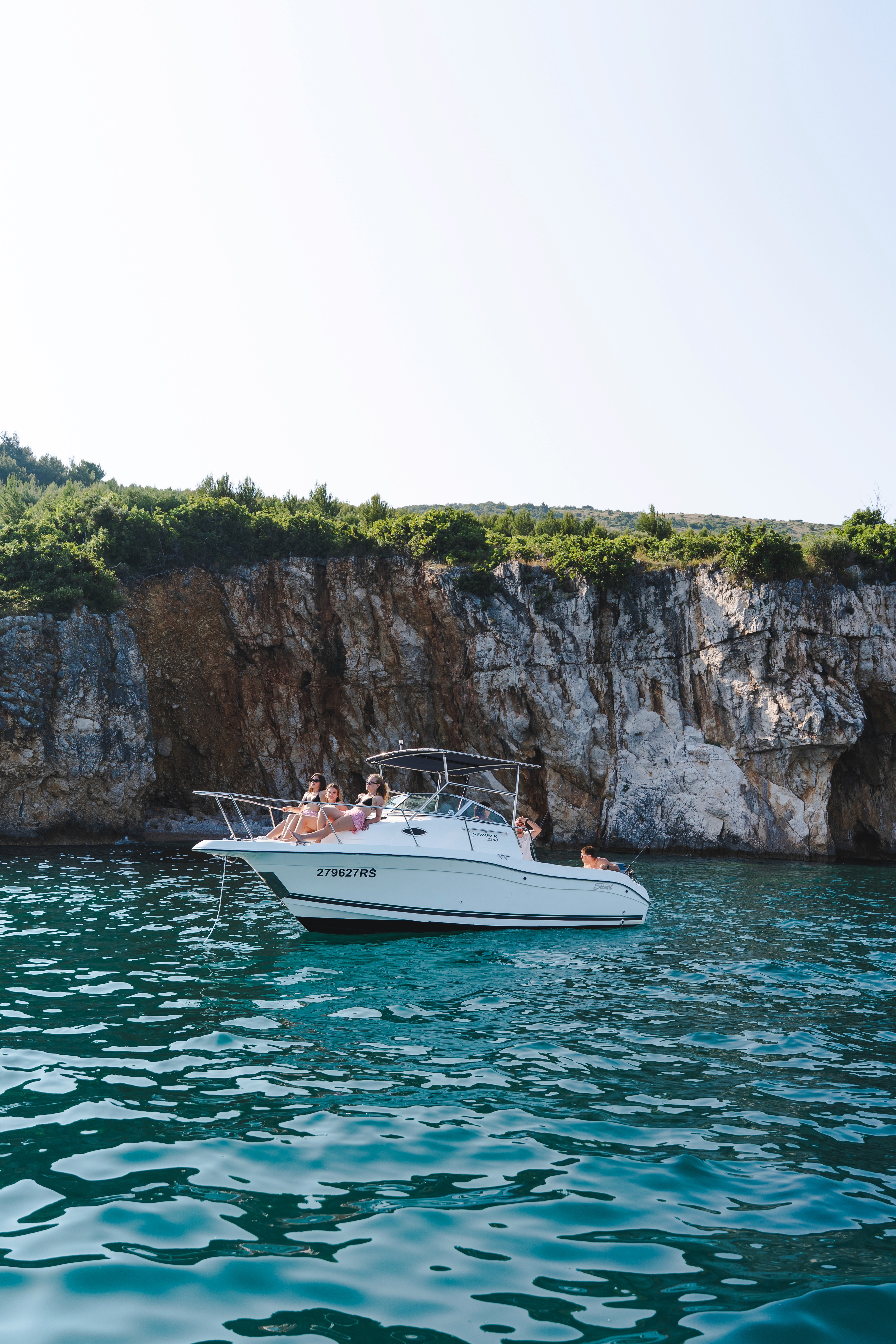 Speedboat with friends enjoying a private boat tour near rocky cliffs on the Adriatic Sea in Croatia.