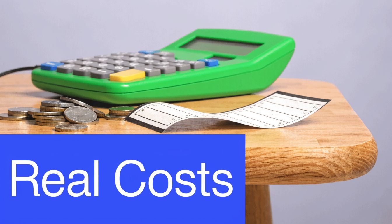 A green calculator, a stack of coins, and a receipt on a wooden table.