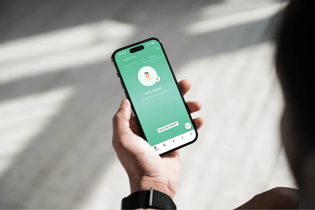 Hånd som holder telefon med Confi.care app