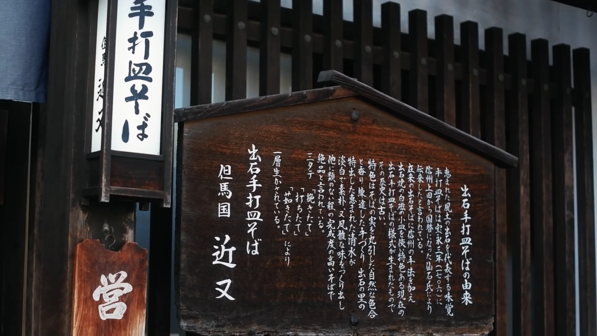 The orange noren and sign of an Izushi sara-soba shop.