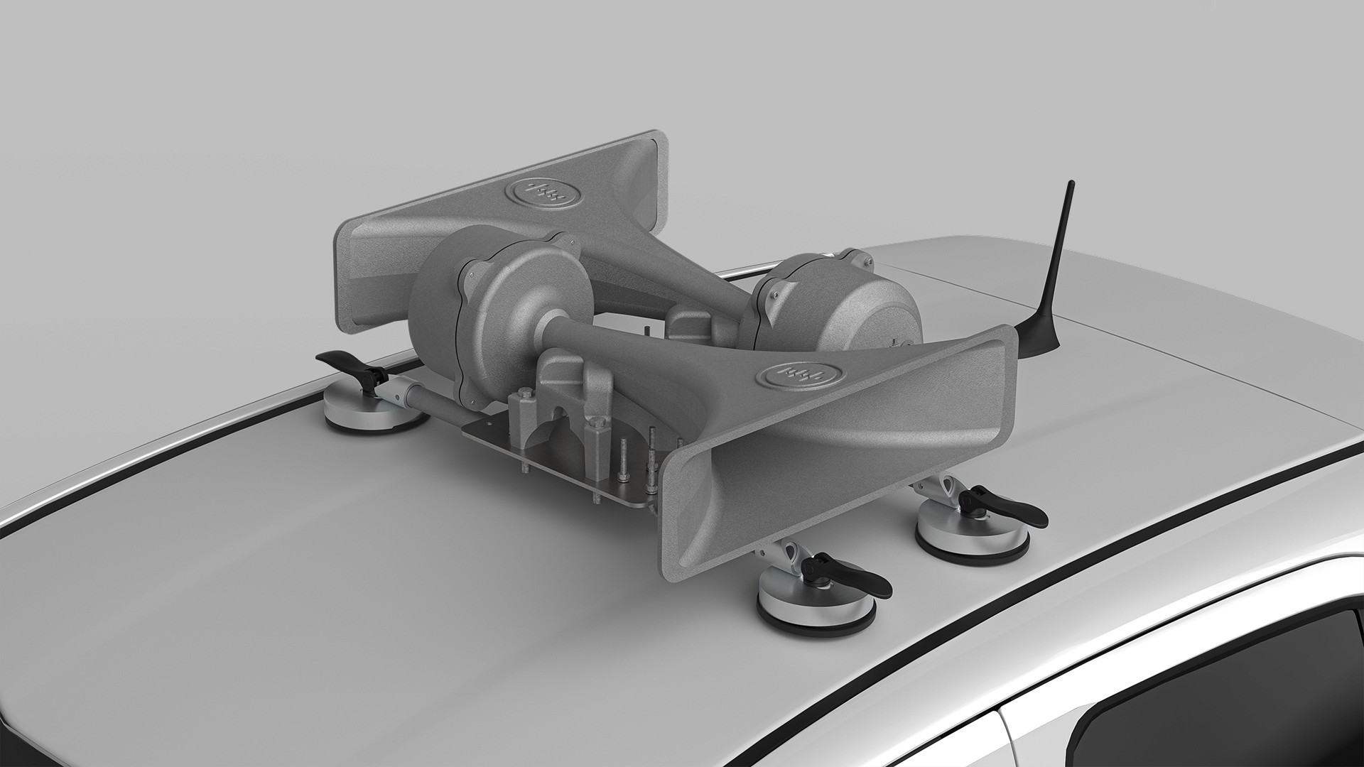 A winding road cuts through rocky terrain, surrounded by patches of green grass and illuminated by sunlight.