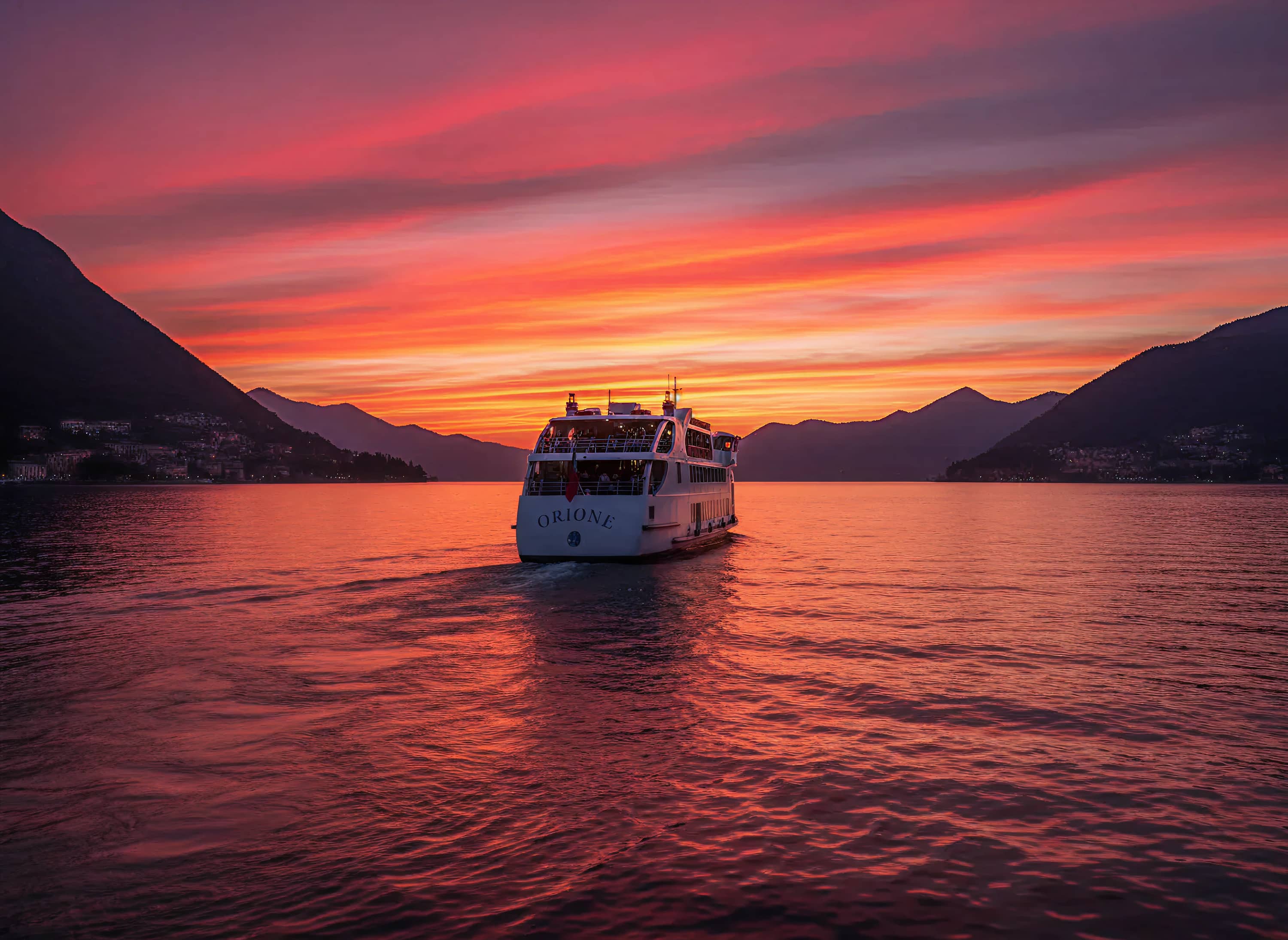 il battello orione che si dirige verso il centro del lago di Como durante il tramonto