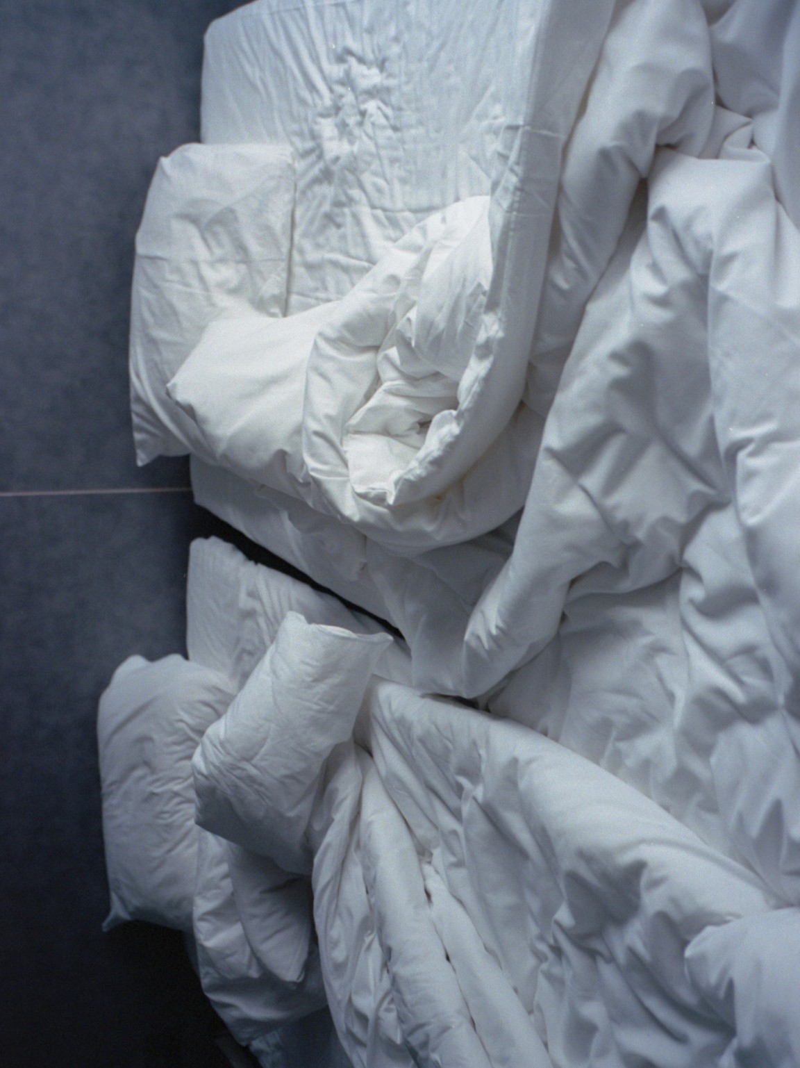 "White rumpled bedding lying on a bed"