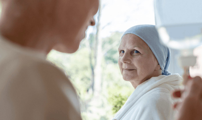 Patient in headscarf smiling at caregiver during treatment.