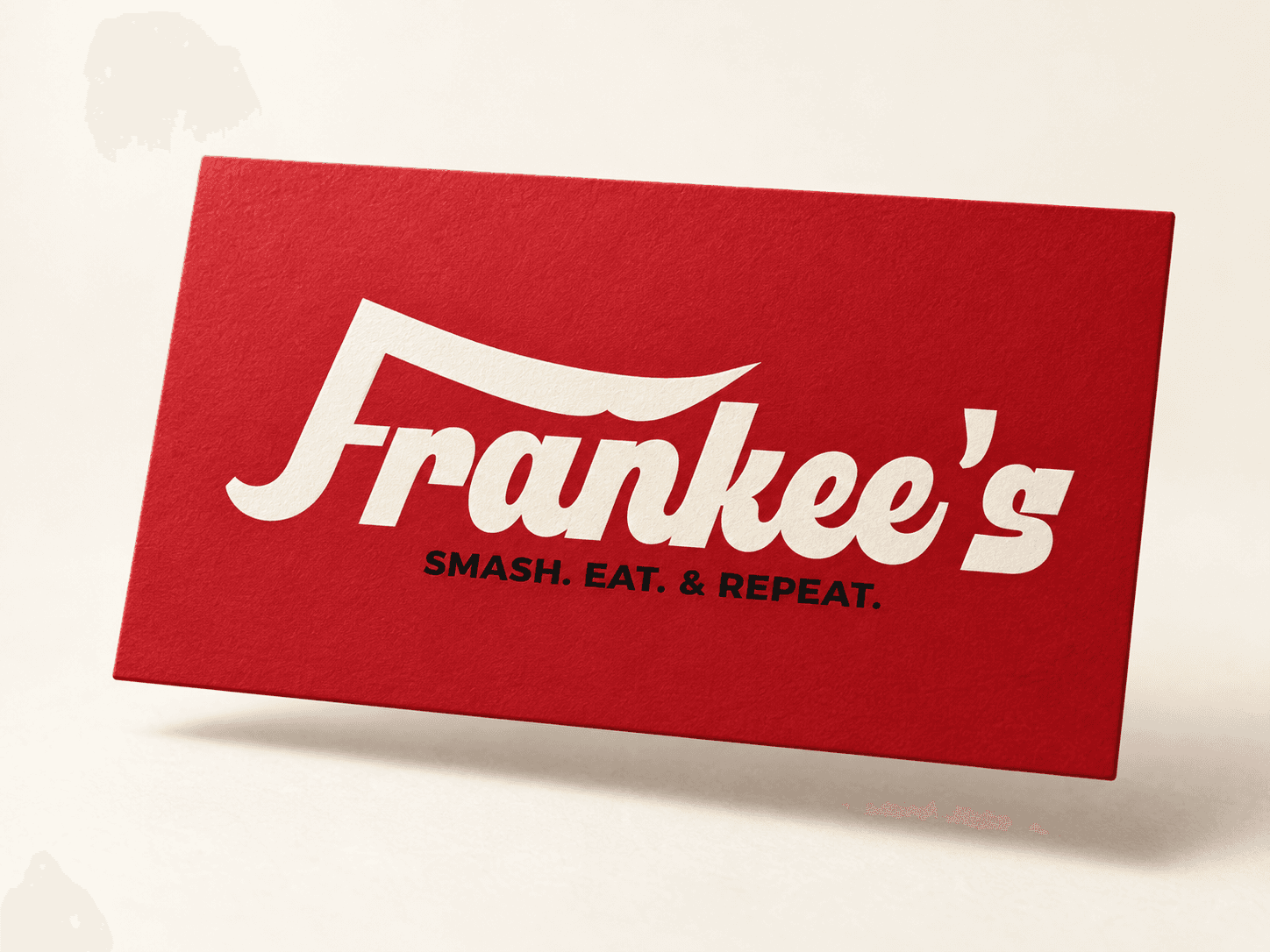 Frankee'nin özel krem rengi kelime markası ve 'Smash. Eat. & Repeat.' sloganı, dokulu kırmızı bir kart üzerinde sunuluyor.