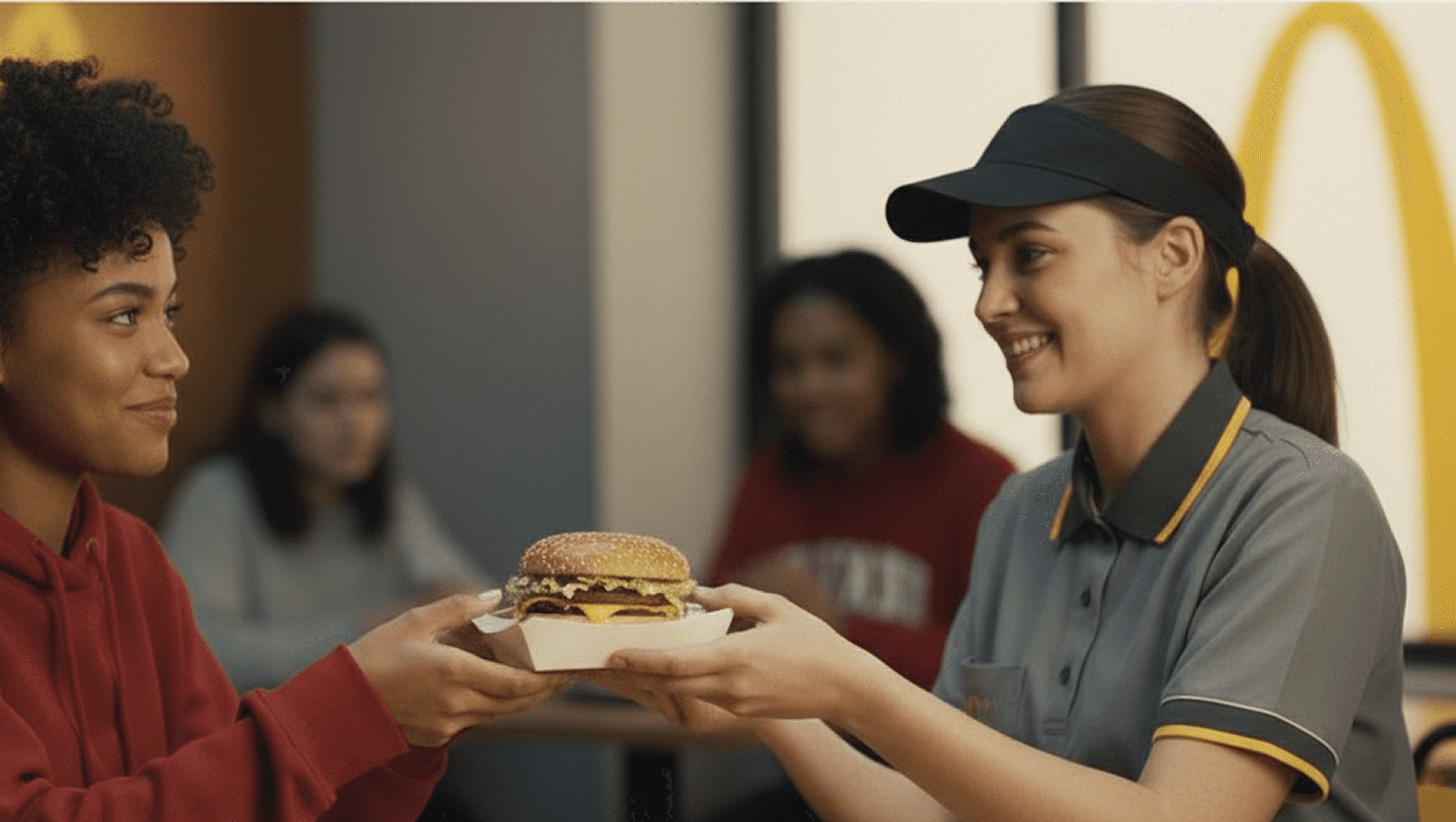 McDonald's staff working handing a burger to a customer