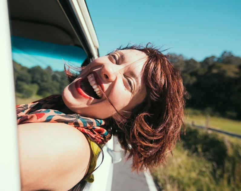 Woman smiling from an open car window on a country road in Kerry, Ireland