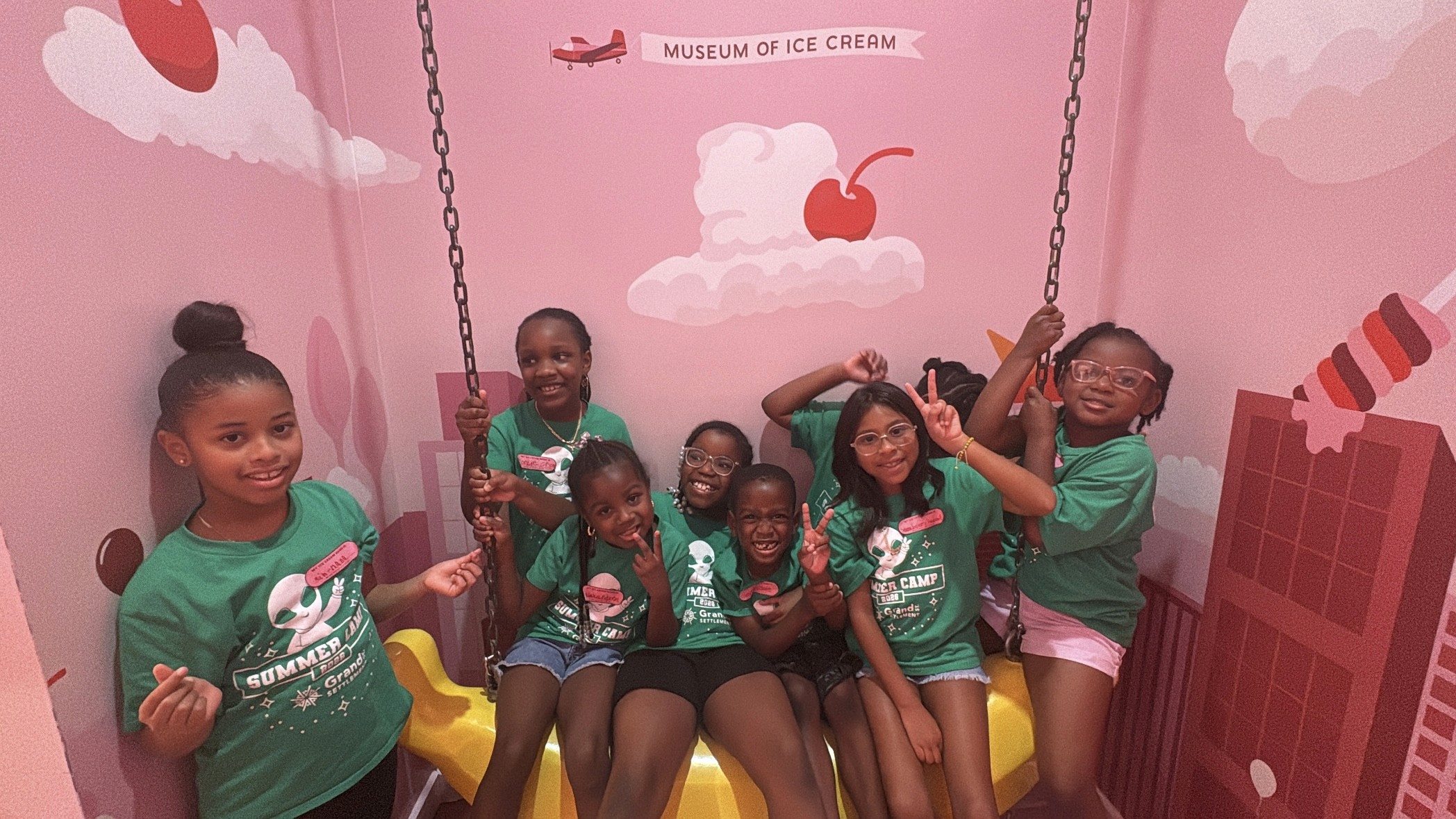 Summer campers sit on a giant plastic banana and make silly faces while in the Museum of Ice Cream.