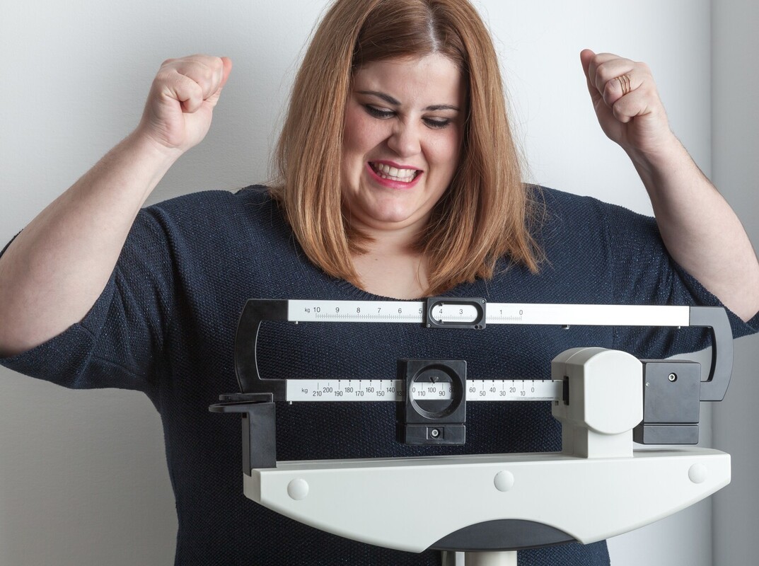 woman cheering in excitement at her results after following a strength training exercise regimen for weight loss