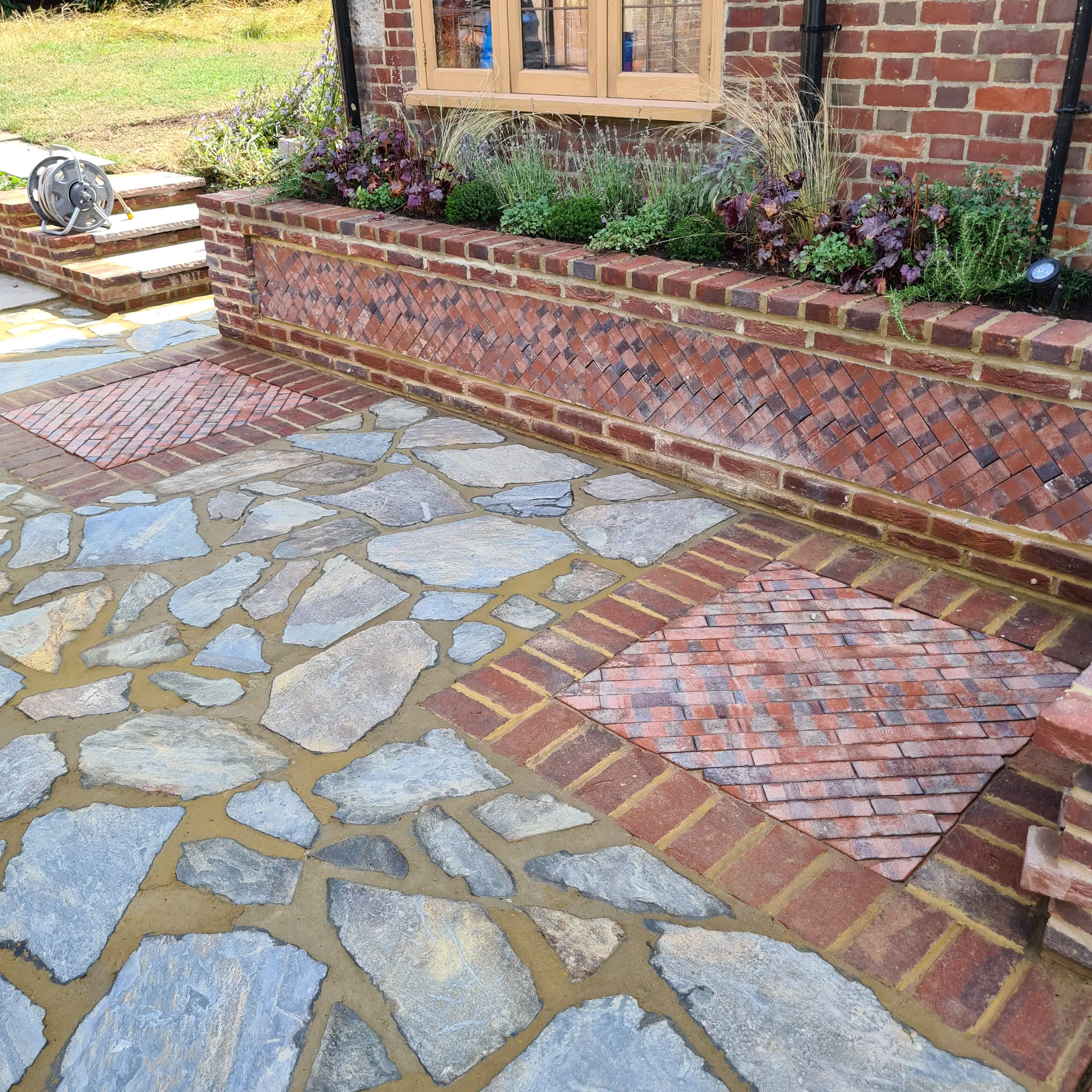 Stone pathway with irregular blue stones and brick accents, leading to a garden area with plants.