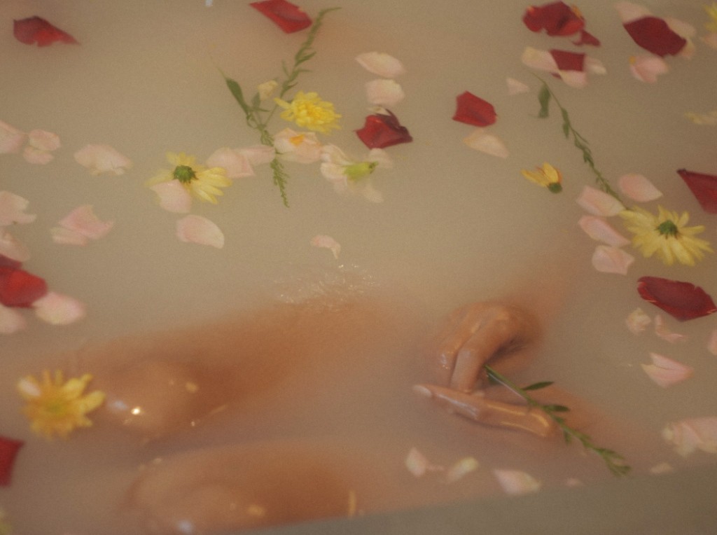 A woman relaxing in soft sunlight, surrounded by plants and warm decor, emphasizing the peaceful and rejuvenating experience of the spa.