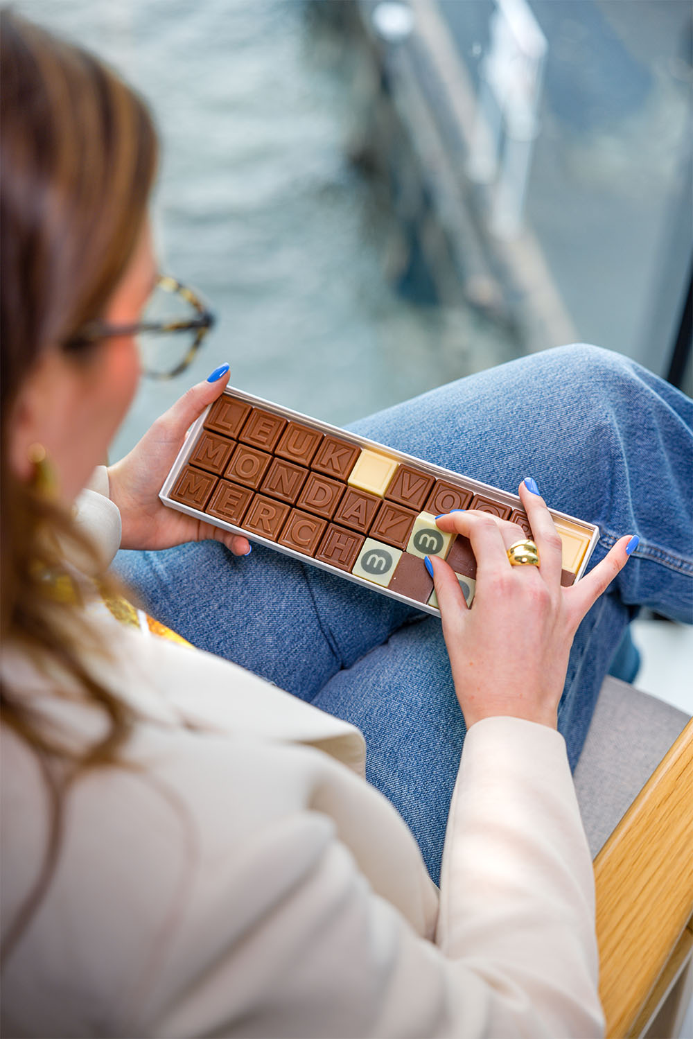 Person holding a tray of chocolates spelling "Leuk voor Monday Merch"
