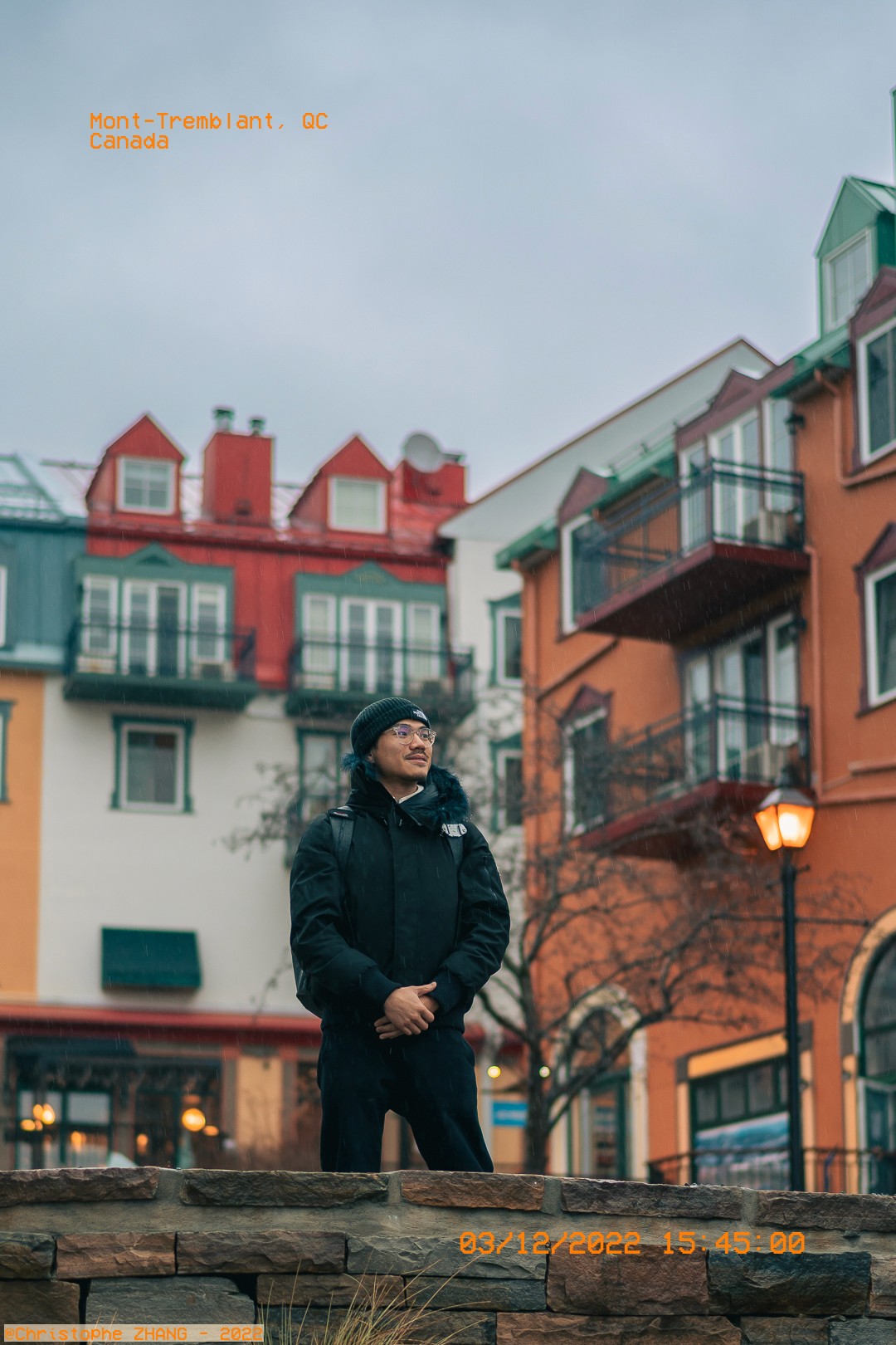 Portrait d'un homme avec un bonnet noir, devant une architecture colorée à Mont-Tremblant.