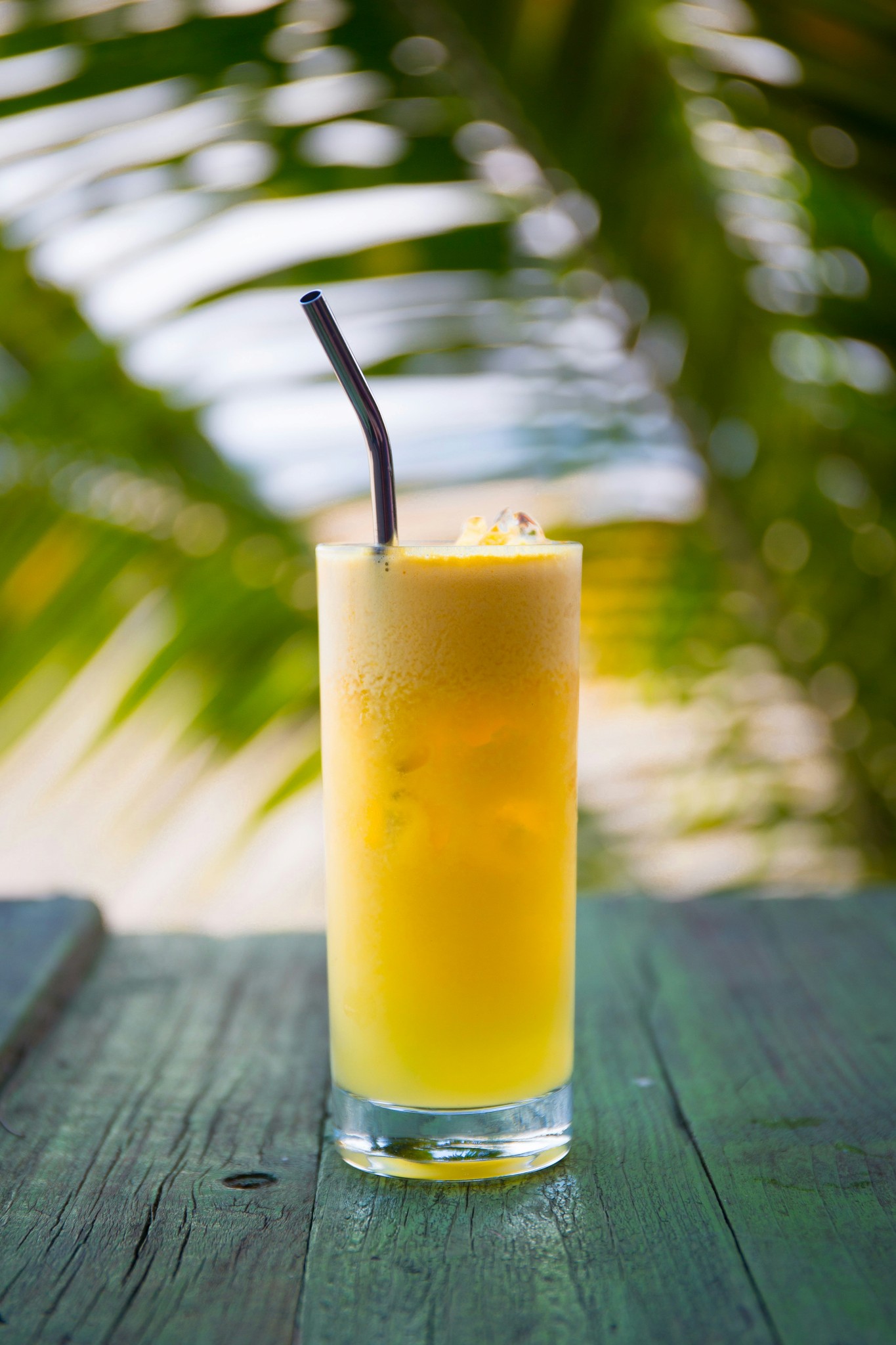 Close up of a drink sitting on a table with palm leave in background