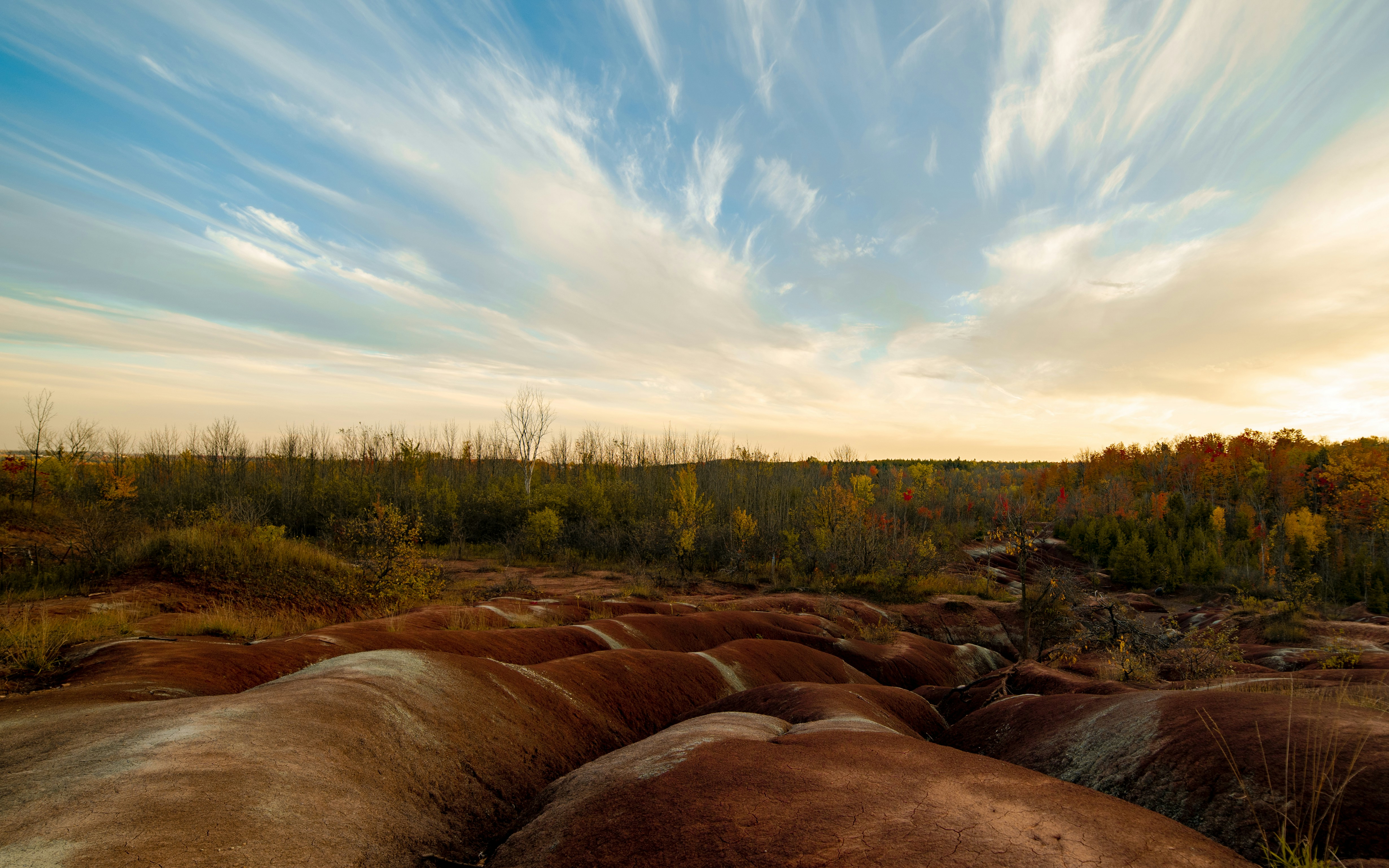 green field near brown rock formations under white and blue sky during daytime