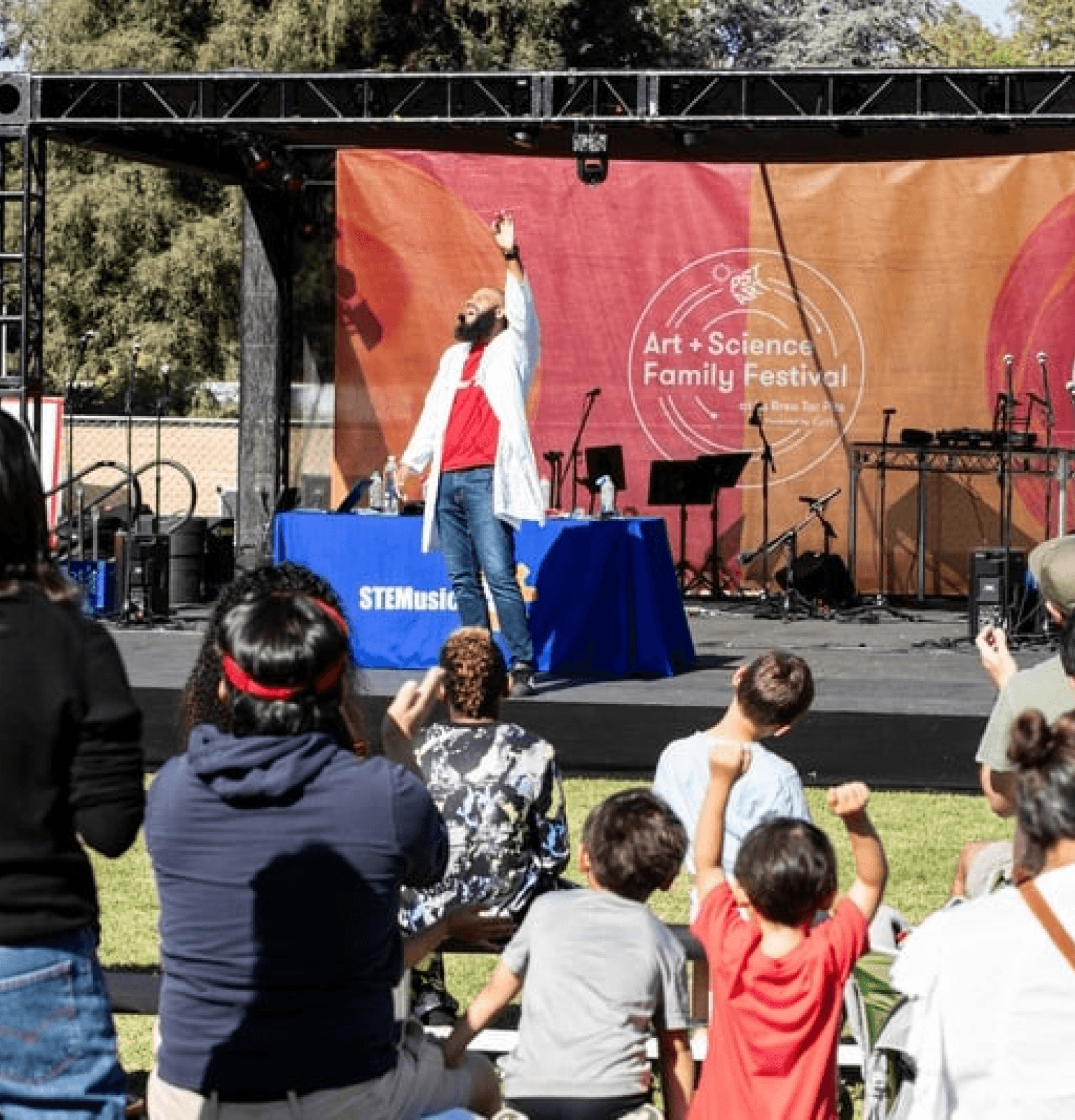 A large crowd watches an exciting live stunt performance at an outdoor festival.