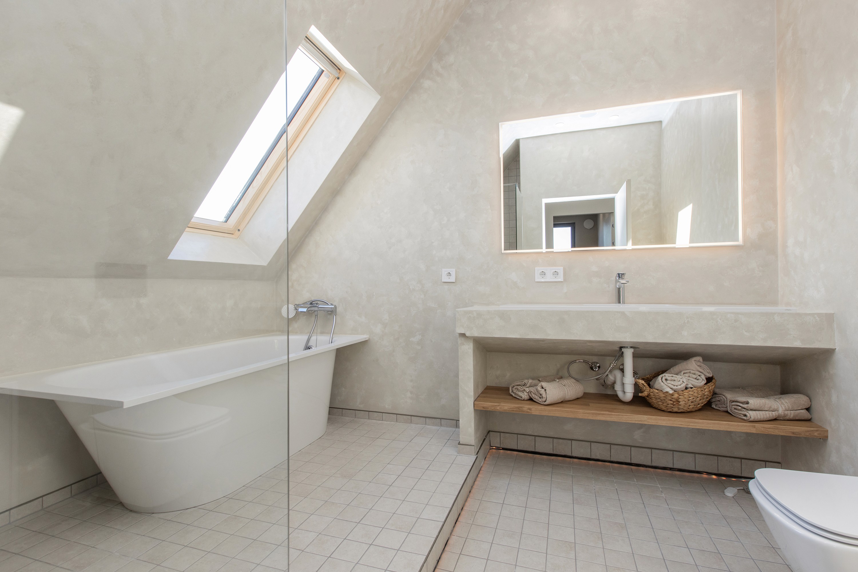 Minimalist bathroom with skylight and neutral tones in Priežavoti Village, reflecting Scandinavian interior design.