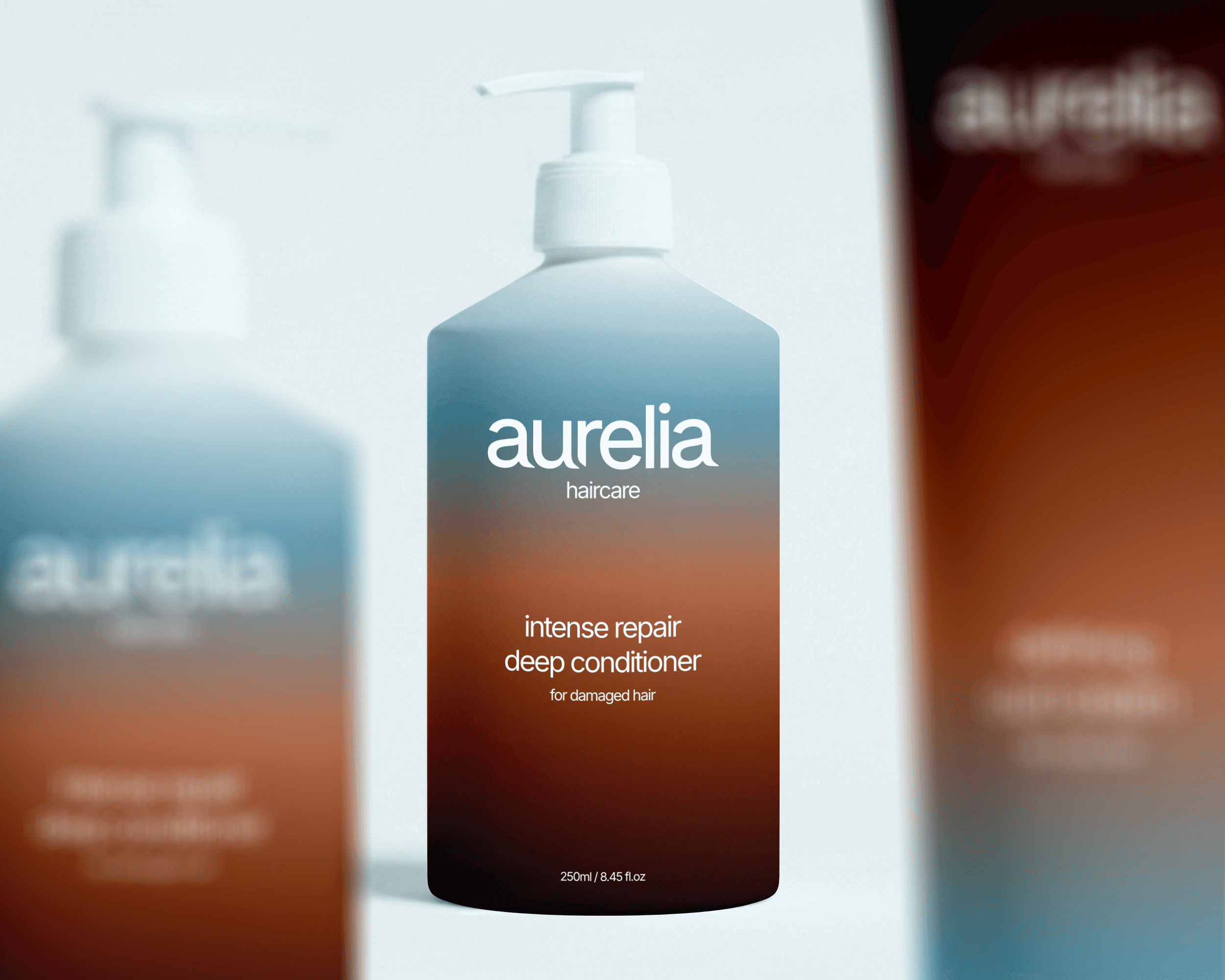 Three haircare product packaging bottles. The bottle in the center is in focus, while the two bottles on either side are blurred. The bottles feature a blue and brown gradient.