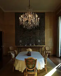 Dramatic dining room with dark walls, crystal chandelier, round table, and ornate decor