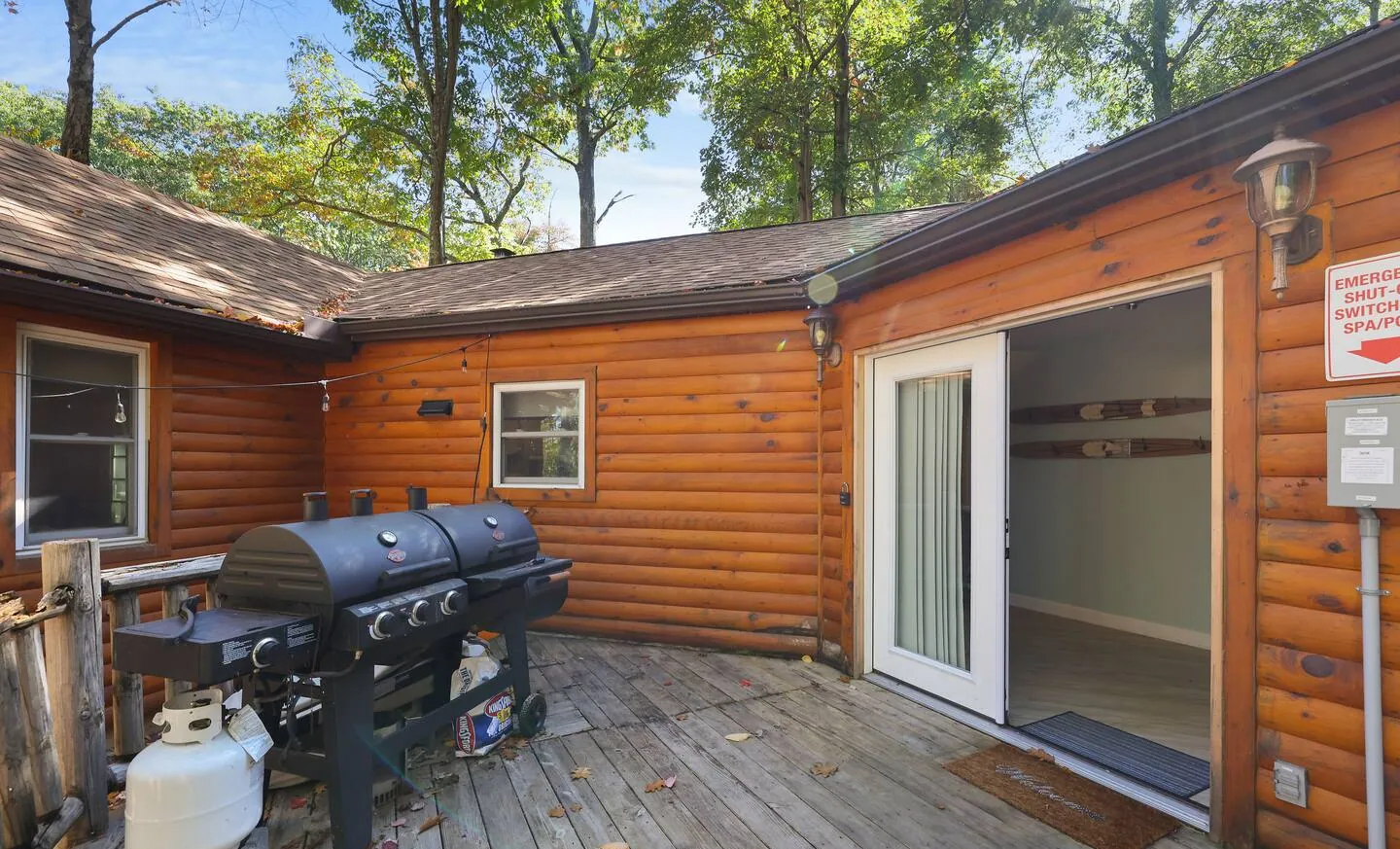 Back deck with gas grill and propane tank beside the log cabin at Barefoot Bungalow, Lake Harmony