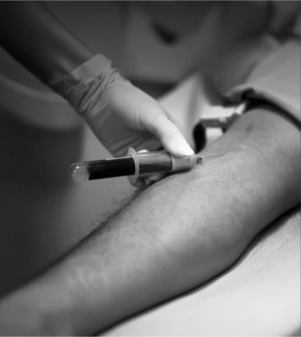 Blood being drawn from a person’s arm by a medical professional.