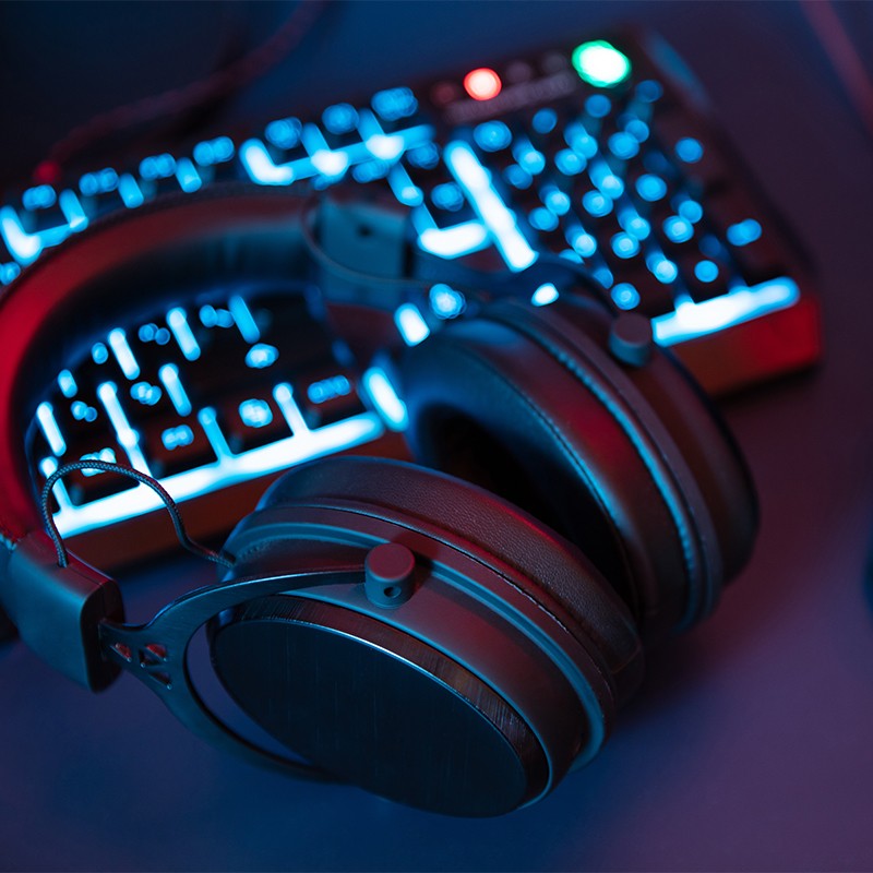 Headset gamer preto apoiado sobre teclado iluminado, destacando a aquisição de acessórios de alta performance pelo consórcio Klubi.