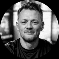 Schwarzweiß-Porträt eines Mannes mit kurzem Haar und leichtem Lächeln