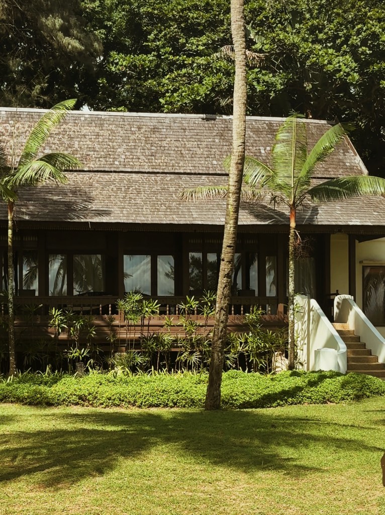 A wooden structure surrounded by palm trees and lush greenery at Tanjong Jara Resort.