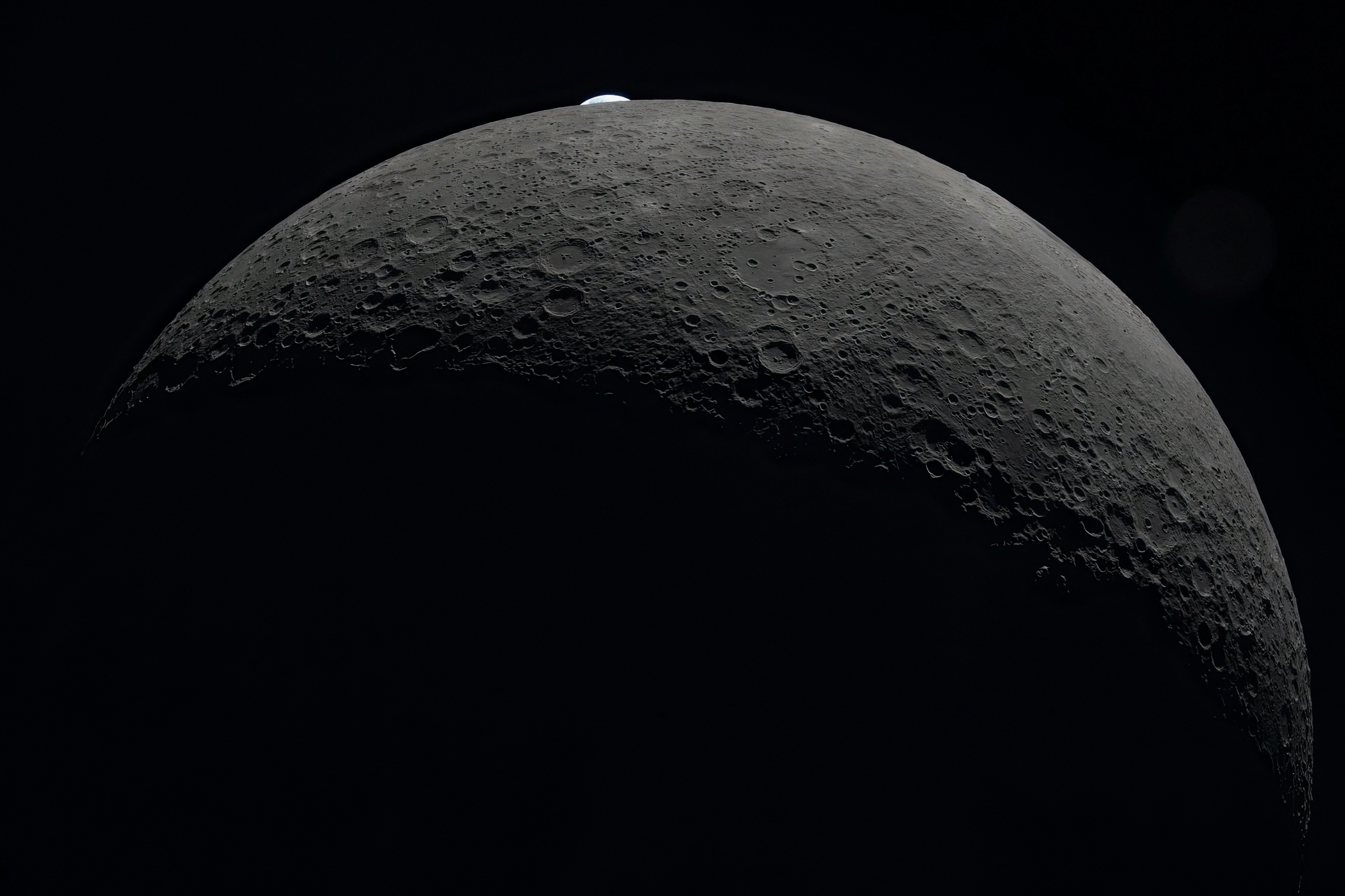 Crescent moon with visible craters against black background