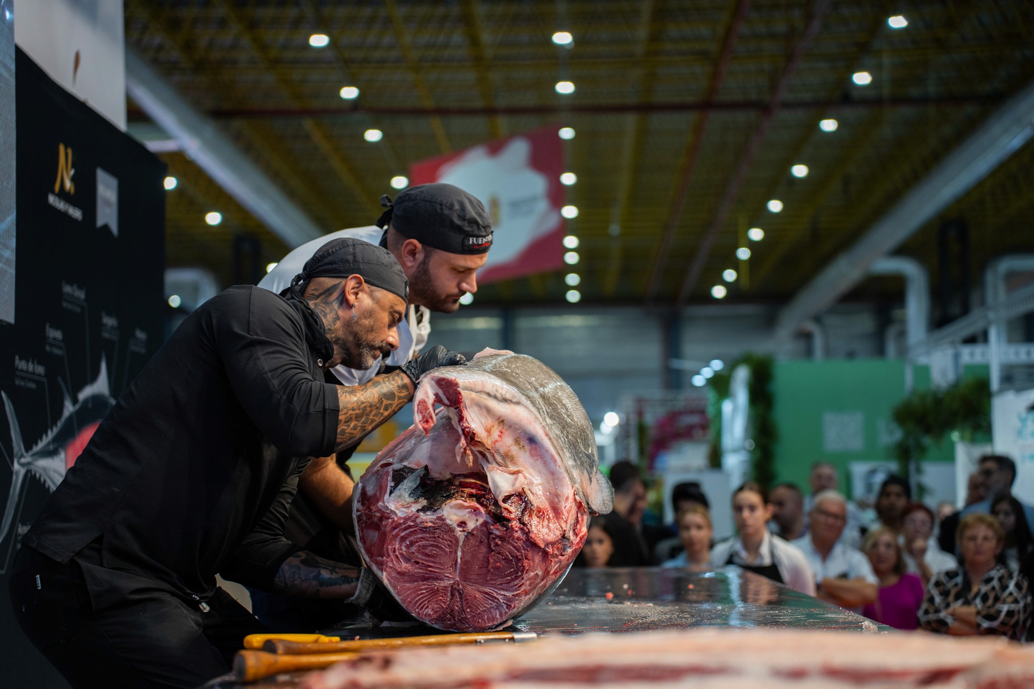 A woman wearing a shiny coat stands in focus, while a blurred background creates a sense of movement.