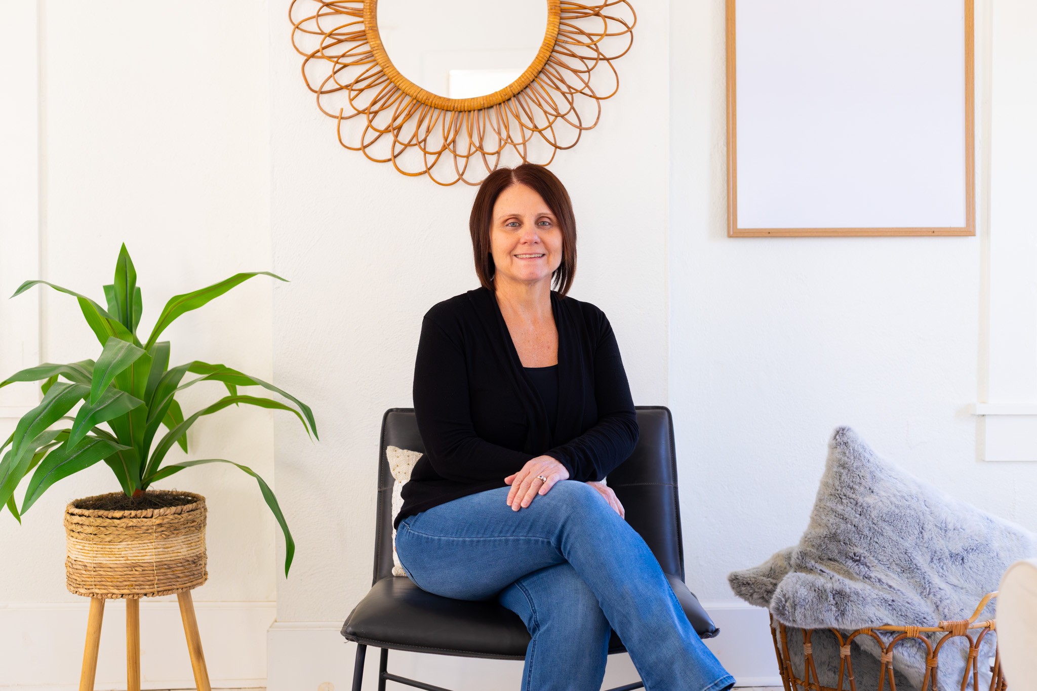 A young person with long, wavy hair sits in front of a plain background, looking directly at the camera.