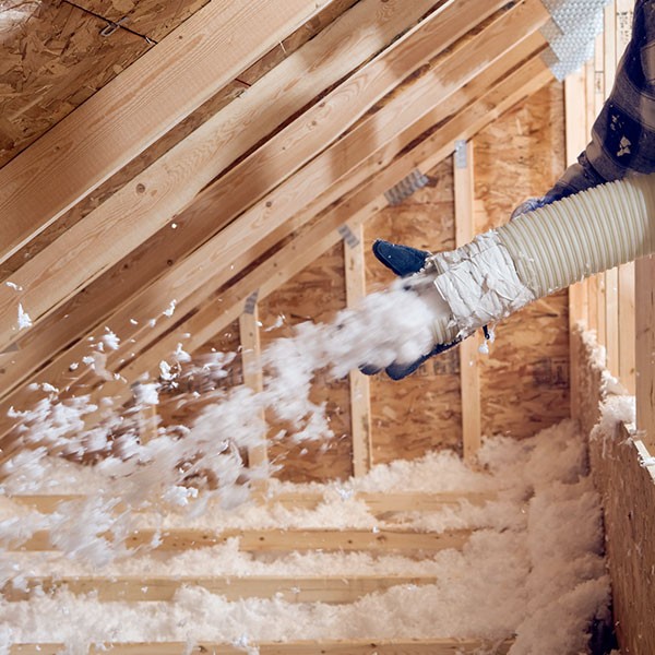 Bild eines Fachmanns, der Dämmmaterial in einen Dachboden einbringt