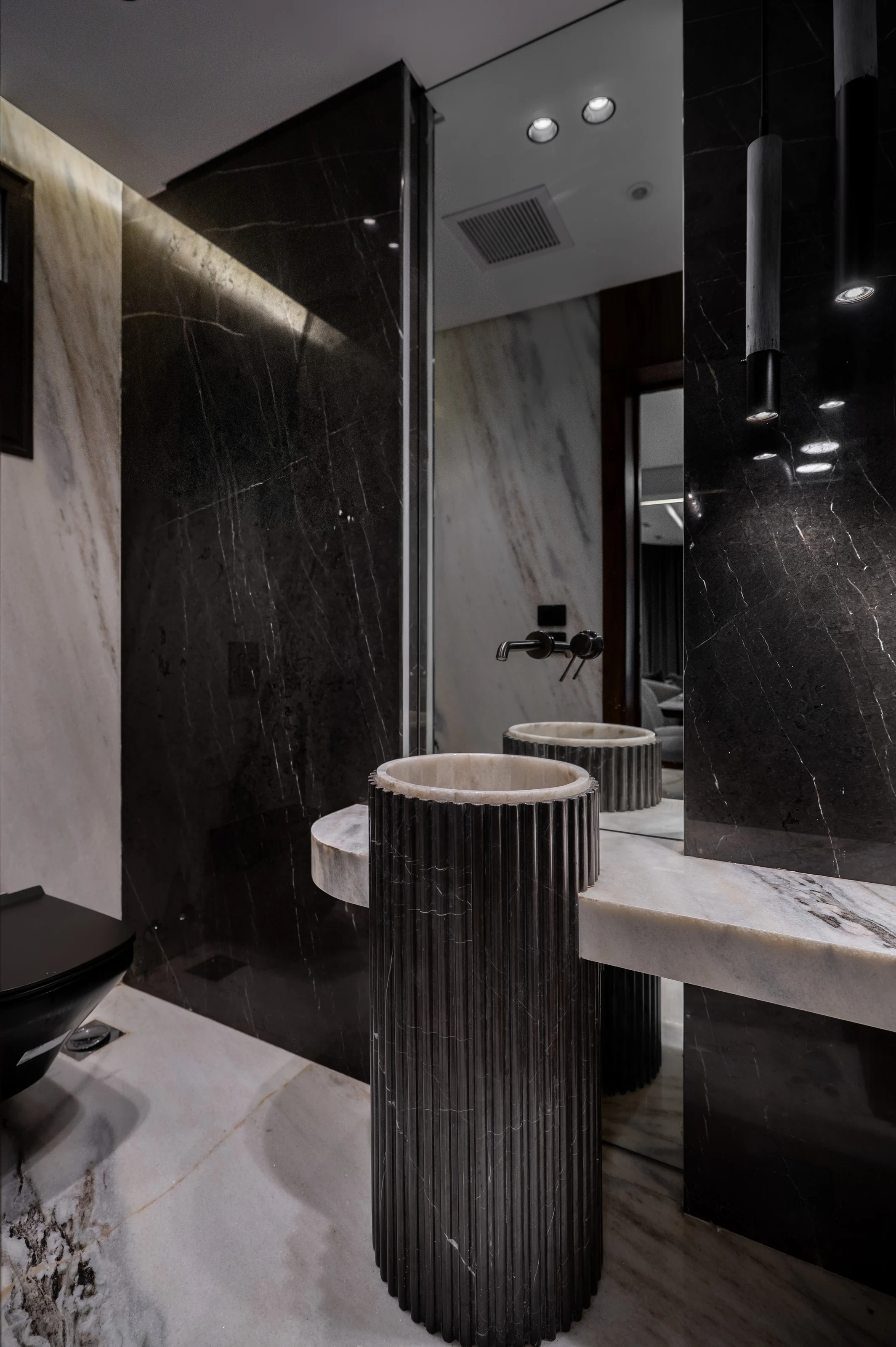 Guest bathroom at Mivida Twin Villa with dark marble walls and sculptural basins.