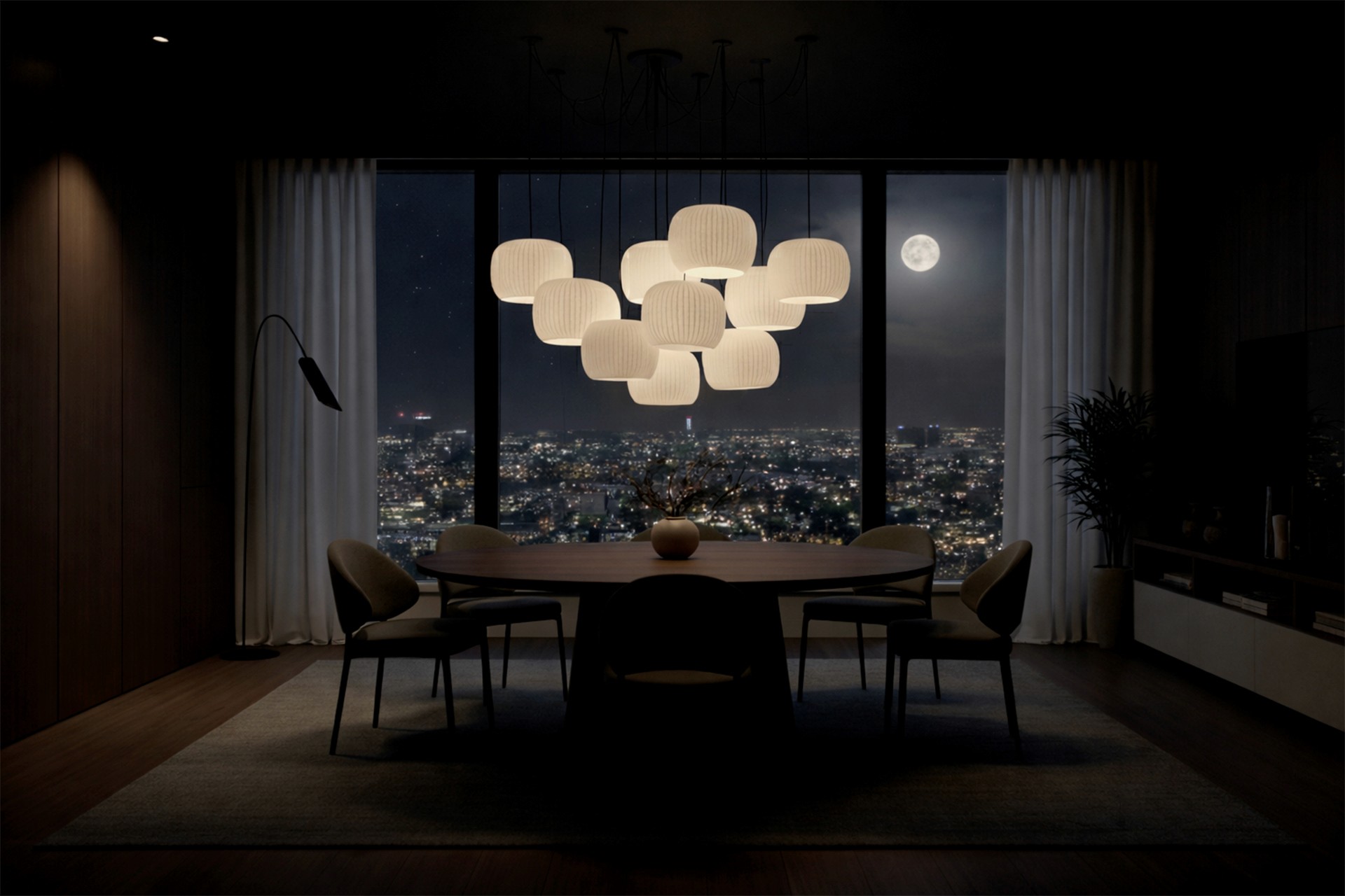 A wide, symmetrical shot of a cloud-like chandelier centered over a dining table, framed by a window showing a full moon and city lights.