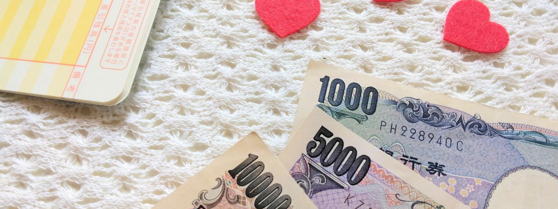 お札と通帳、赤いハートが置かれた暖かい雰囲気のテーブル